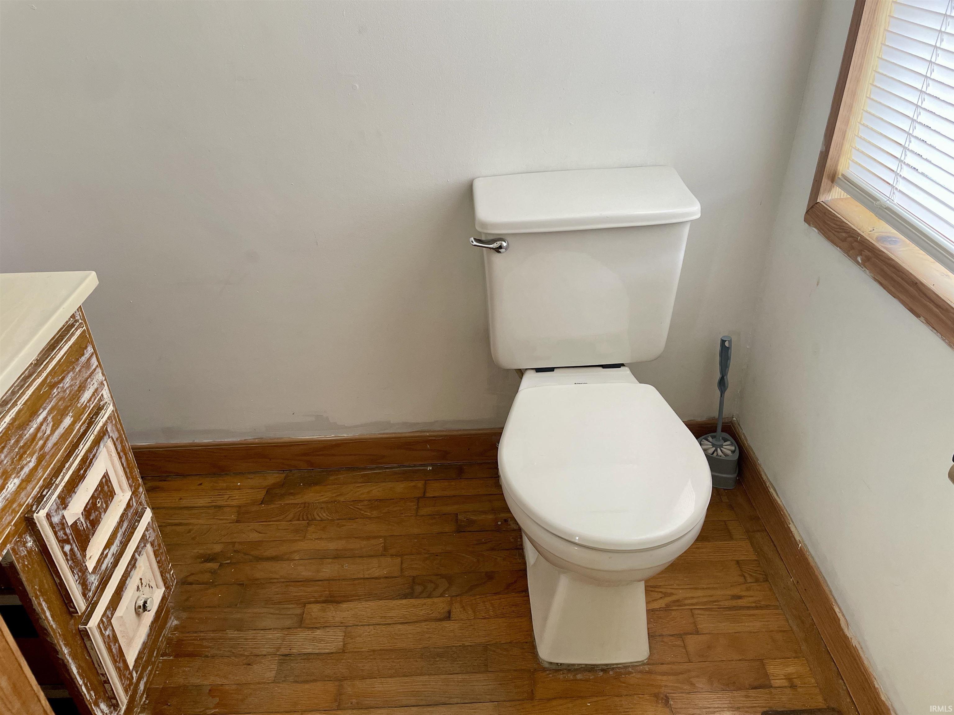 Half bathroom featuring wood-type flooring and toilet