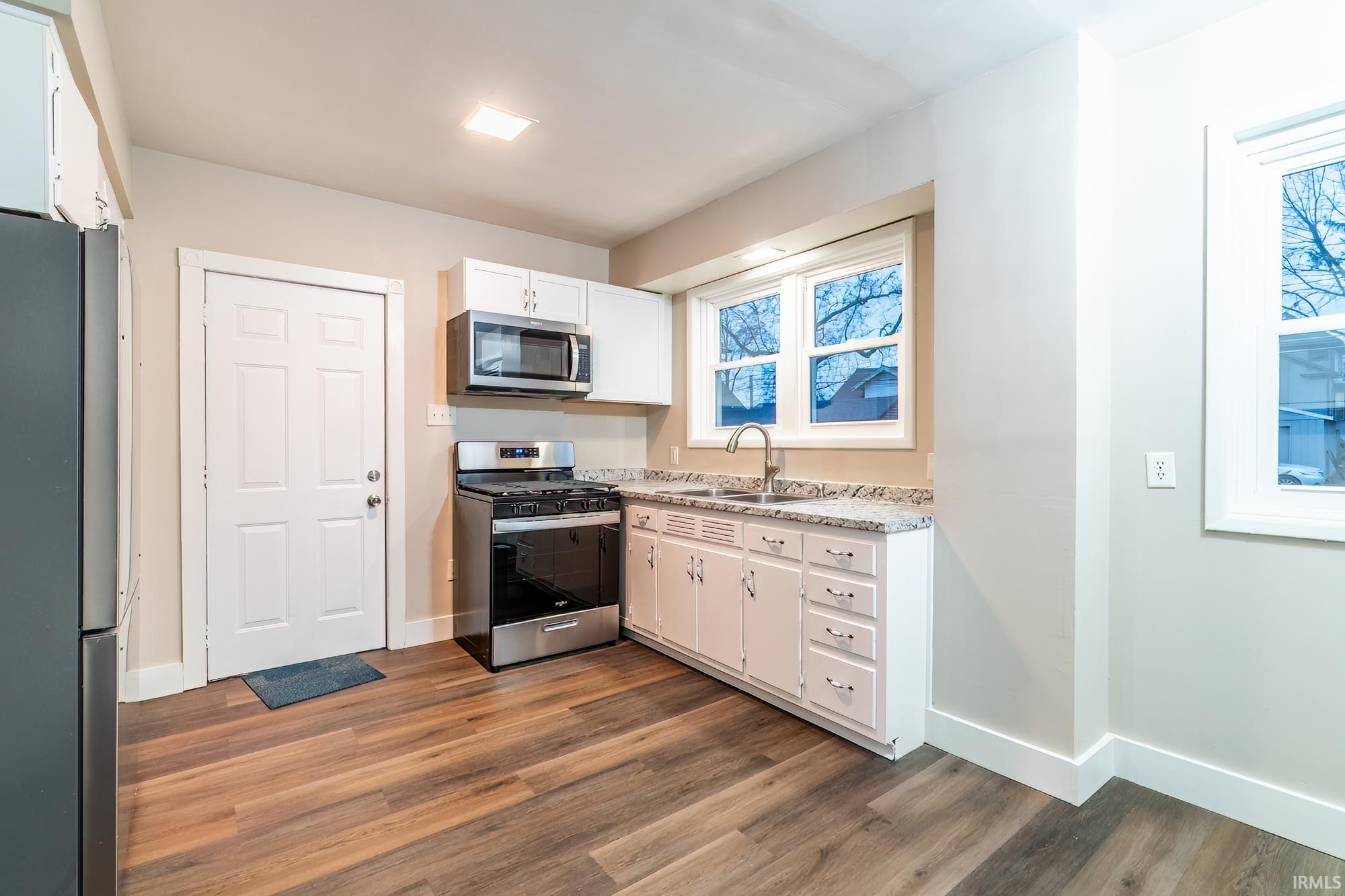 Kitchen featuring stainless steel appliances, white cabinetry, and dark wood finished floors