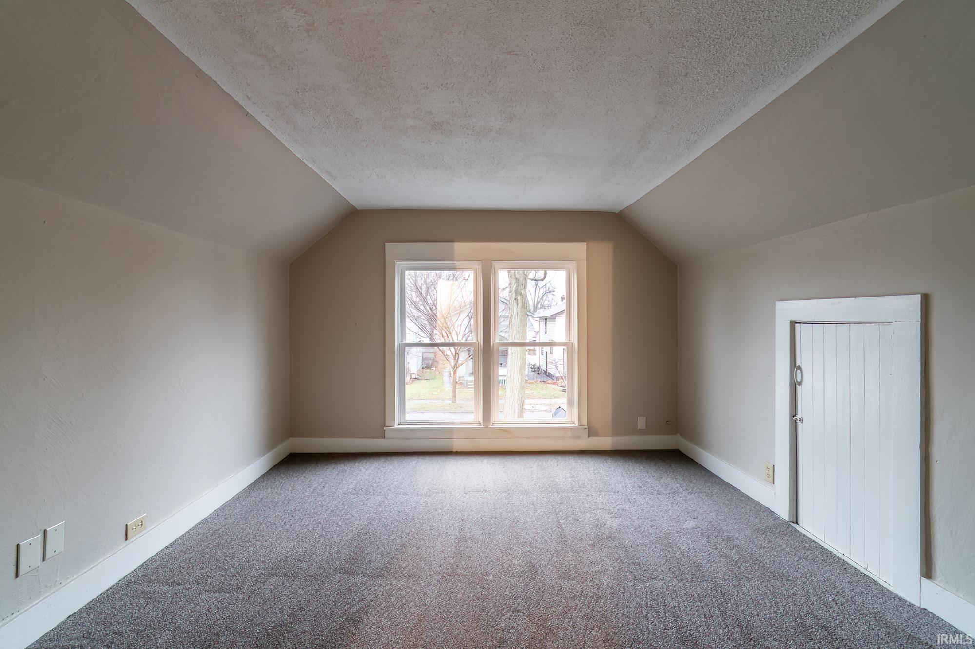 Additional living space with vaulted ceiling, carpet, and a textured ceiling