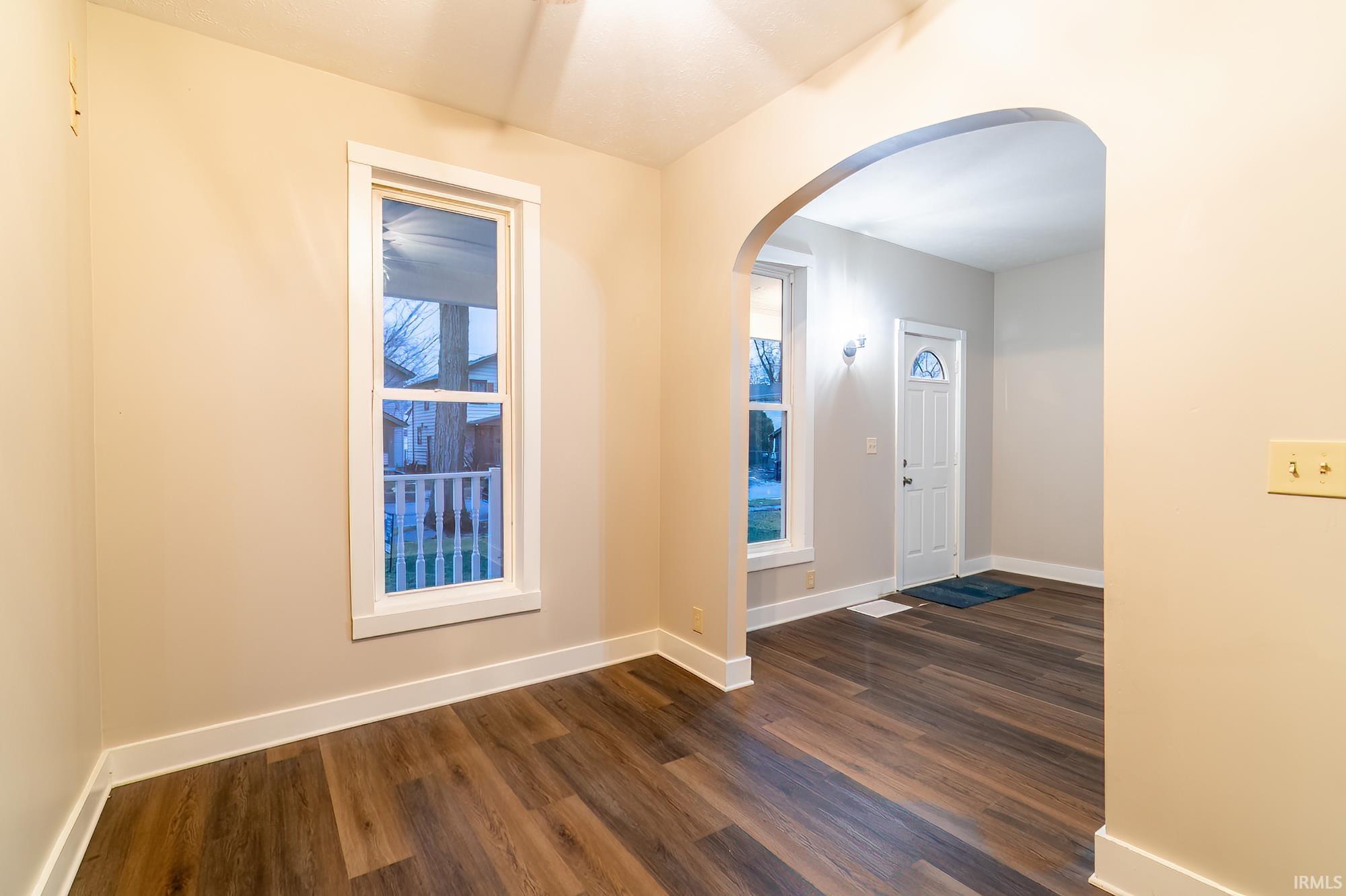 Foyer featuring arched walkways, dark wood-style flooring, and plenty of natural light