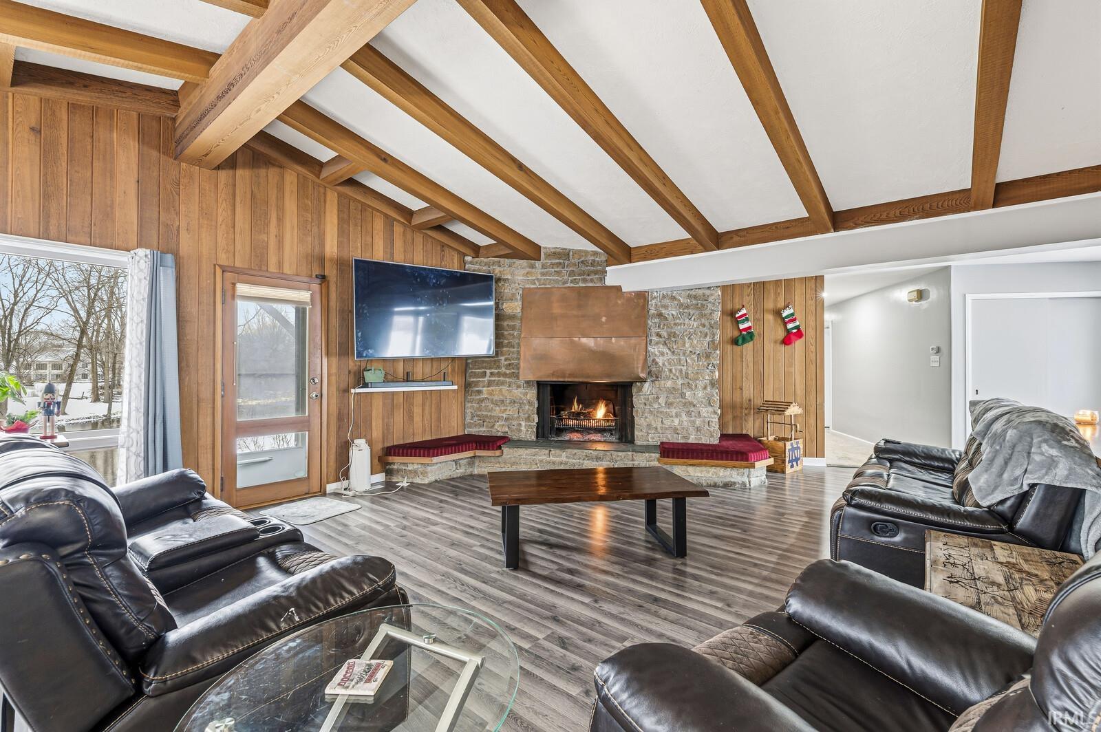 Living area with a fireplace, wood walls, and wood finished floors