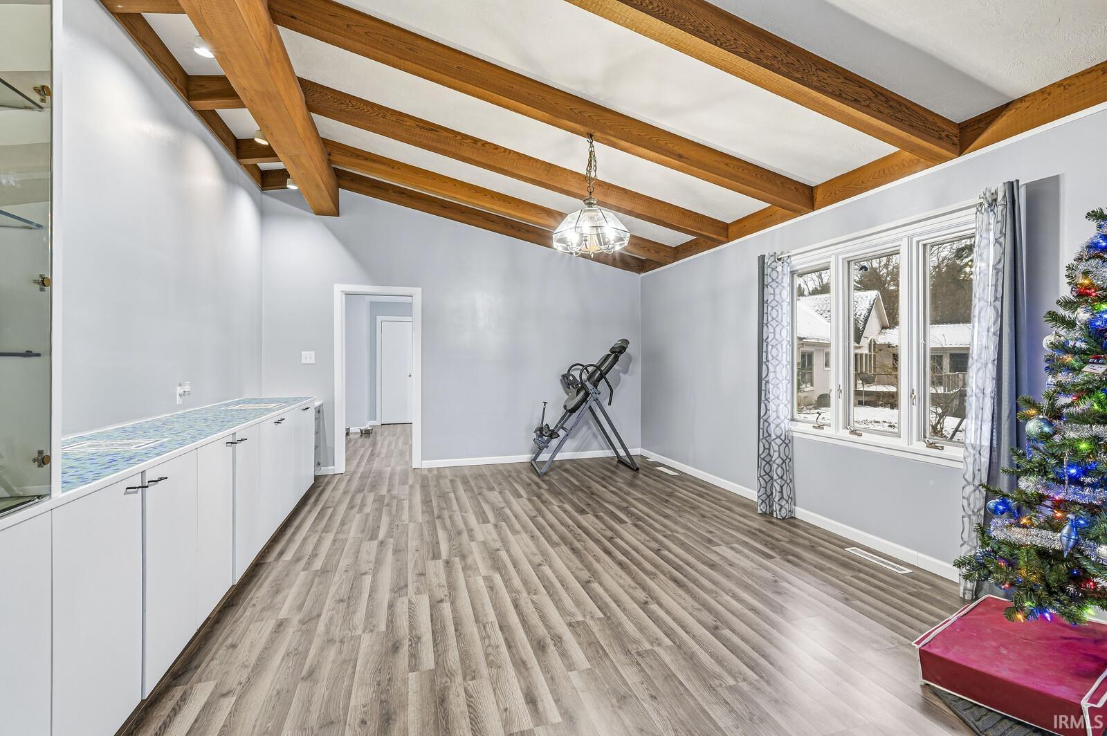 Interior space with hanging light fixtures, white cabinetry, light wood-style flooring, and light countertops