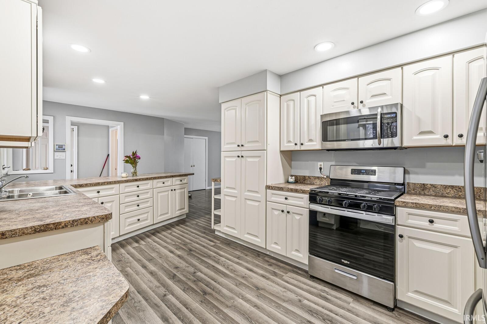Kitchen featuring appliances with stainless steel finishes, recessed lighting, light wood-style flooring, white cabinets, and light countertops