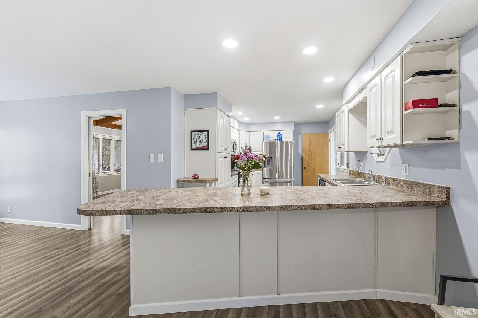 Kitchen featuring a peninsula, white cabinets, stainless steel refrigerator with ice dispenser, and recessed lighting.