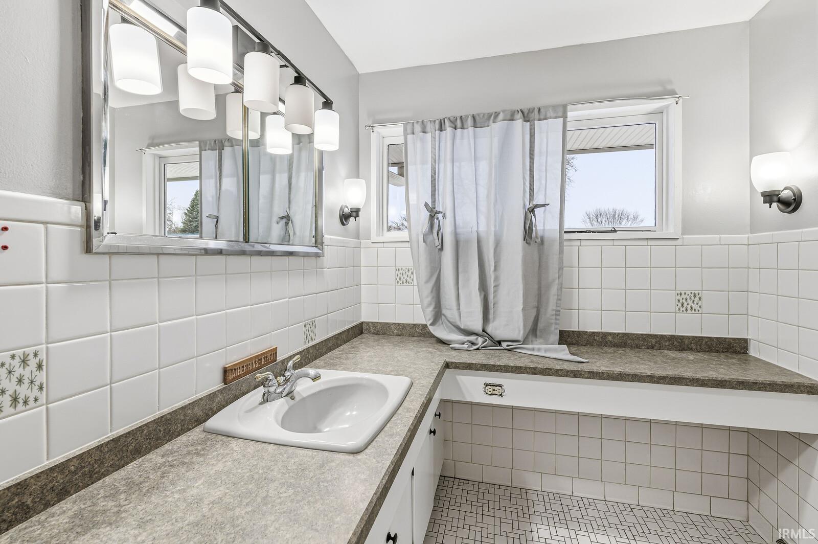Full bath with vanity and tile walls