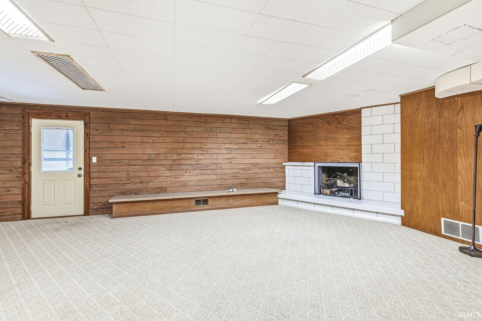 Basement second living room featuring wood walls, carpet, and a fireplace with raised hearth