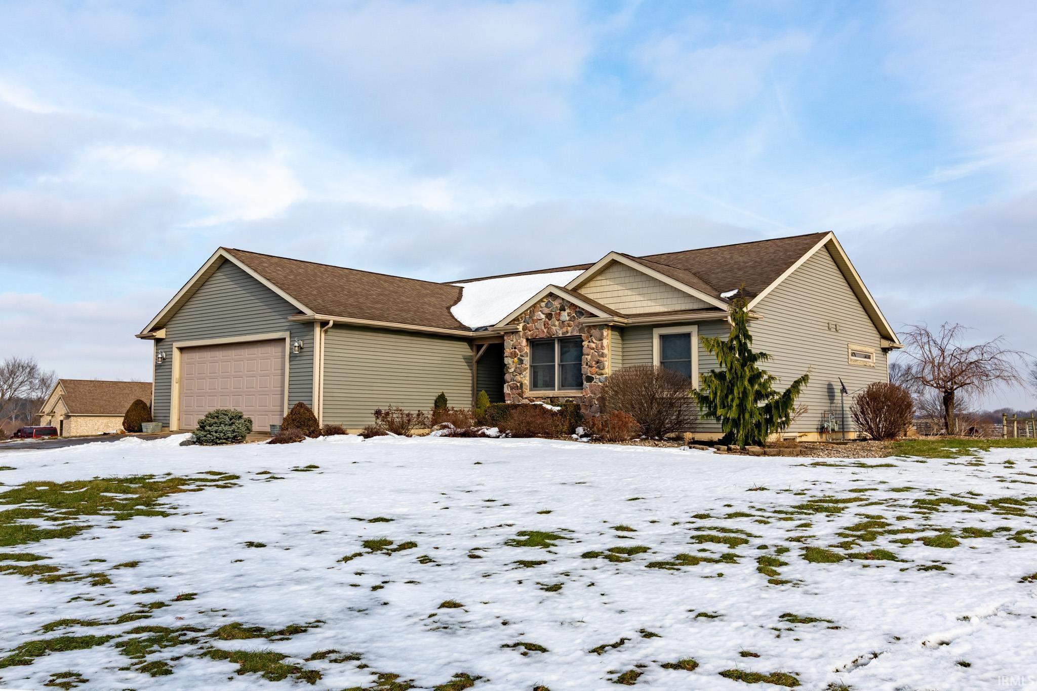 View of front of property with a garage and stone siding