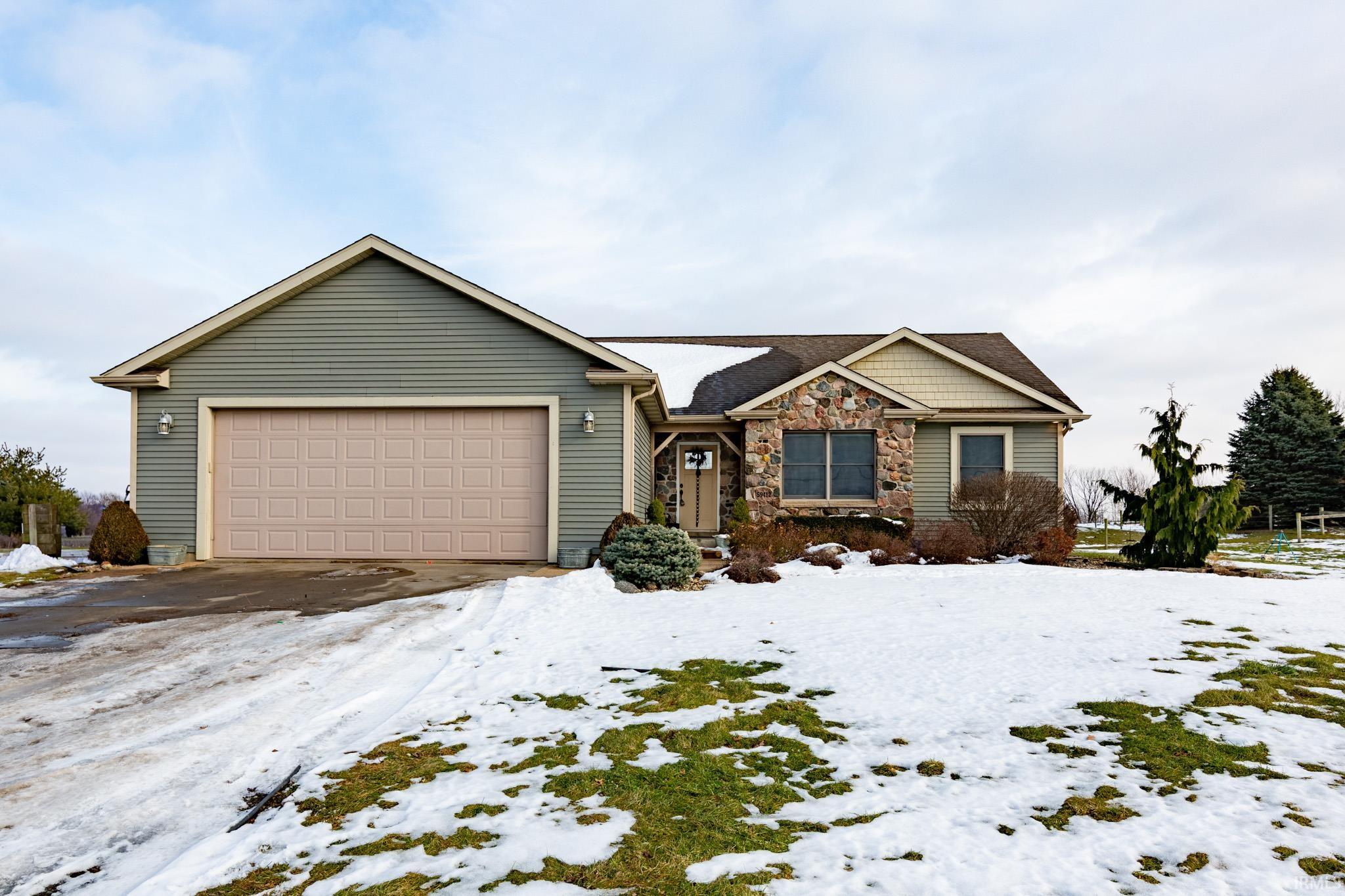 View of front facade with stone siding, a garage, and driveway