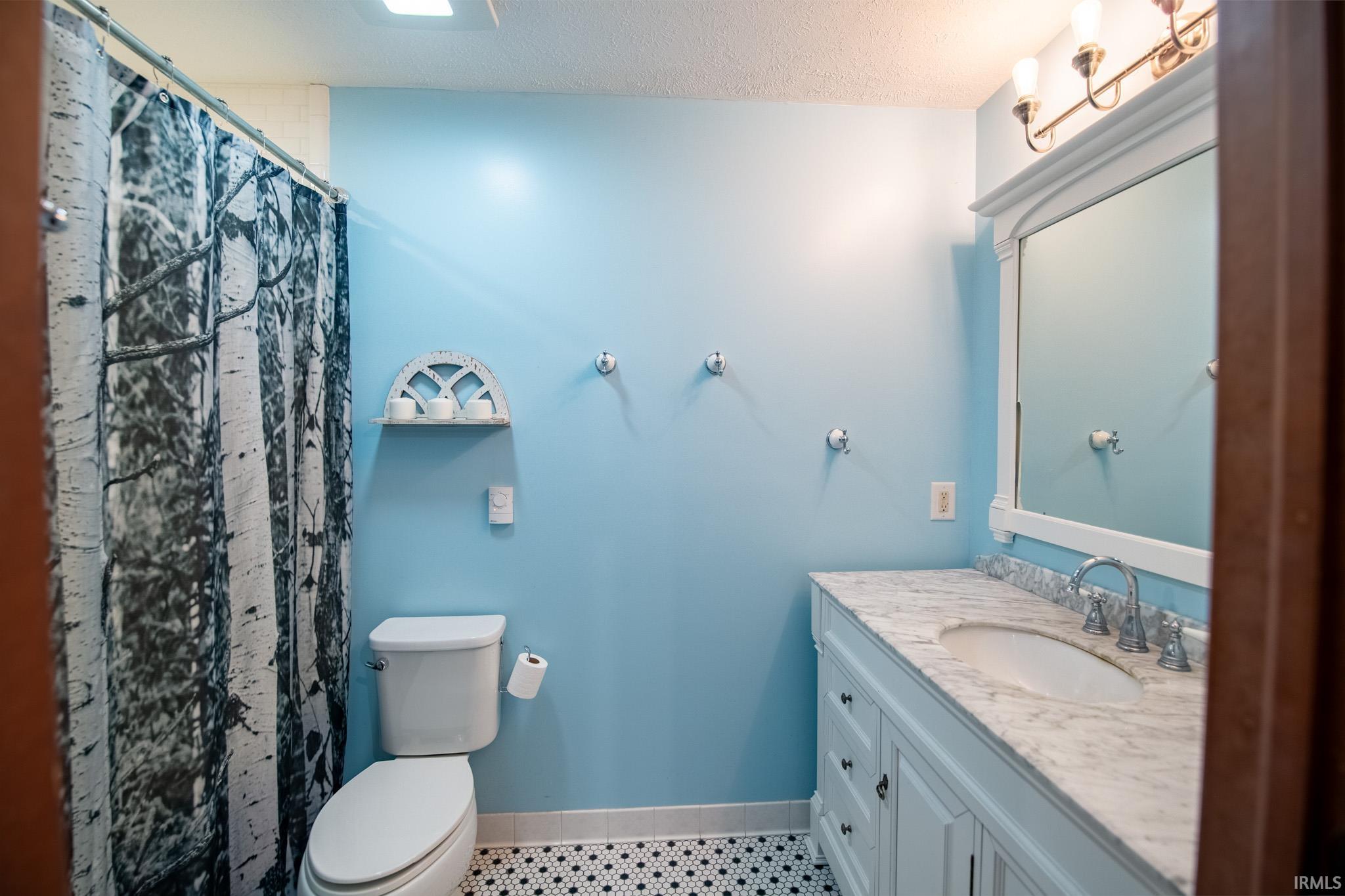 Full bath featuring a shower with curtain, vanity, a textured ceiling, and light tile patterned floors