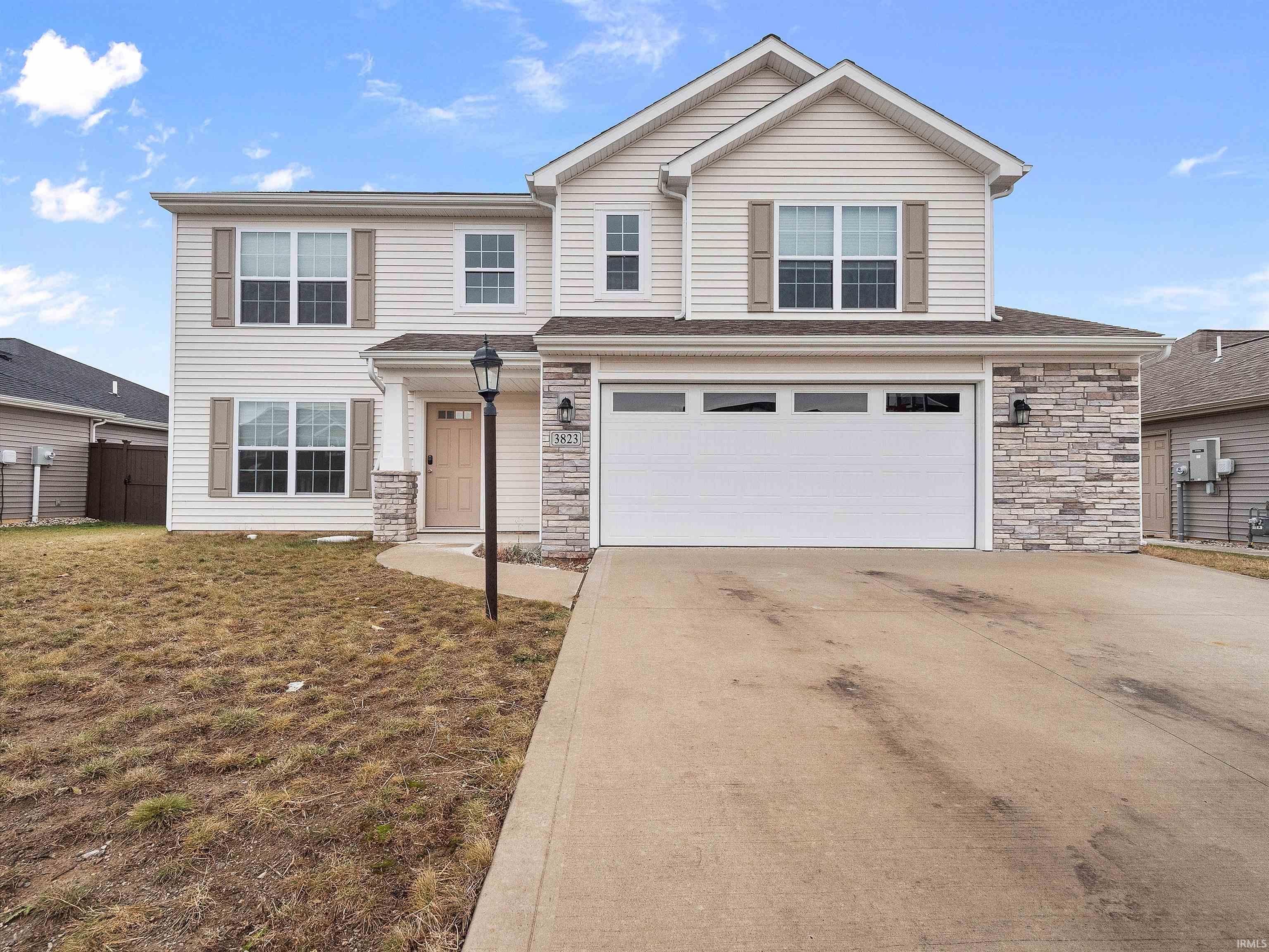 Traditional-style home with stone siding, an attached garage, and concrete driveway