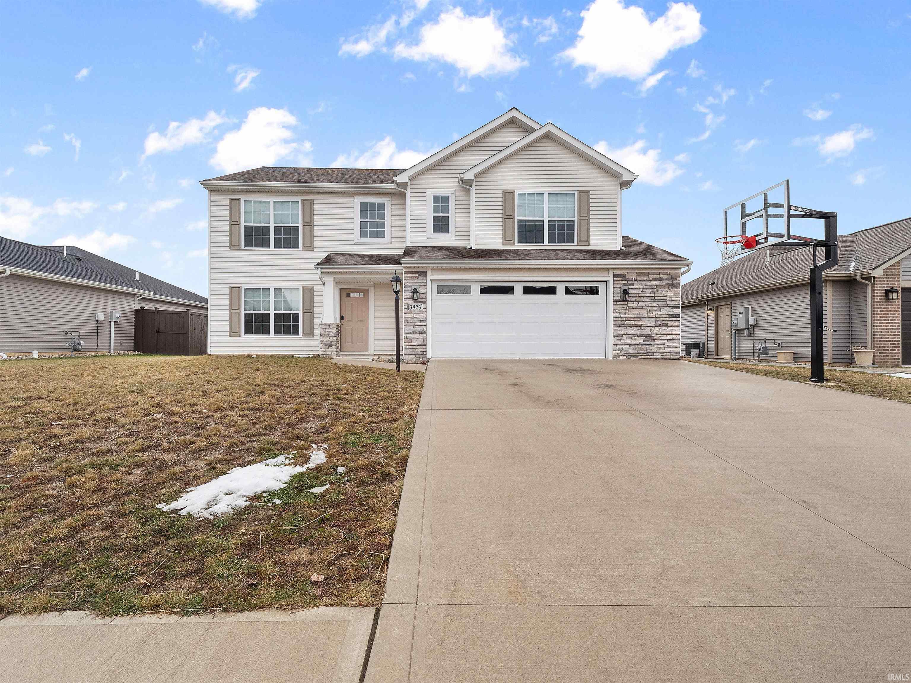 Traditional-style house with stone siding, driveway, a garage, and a front yard