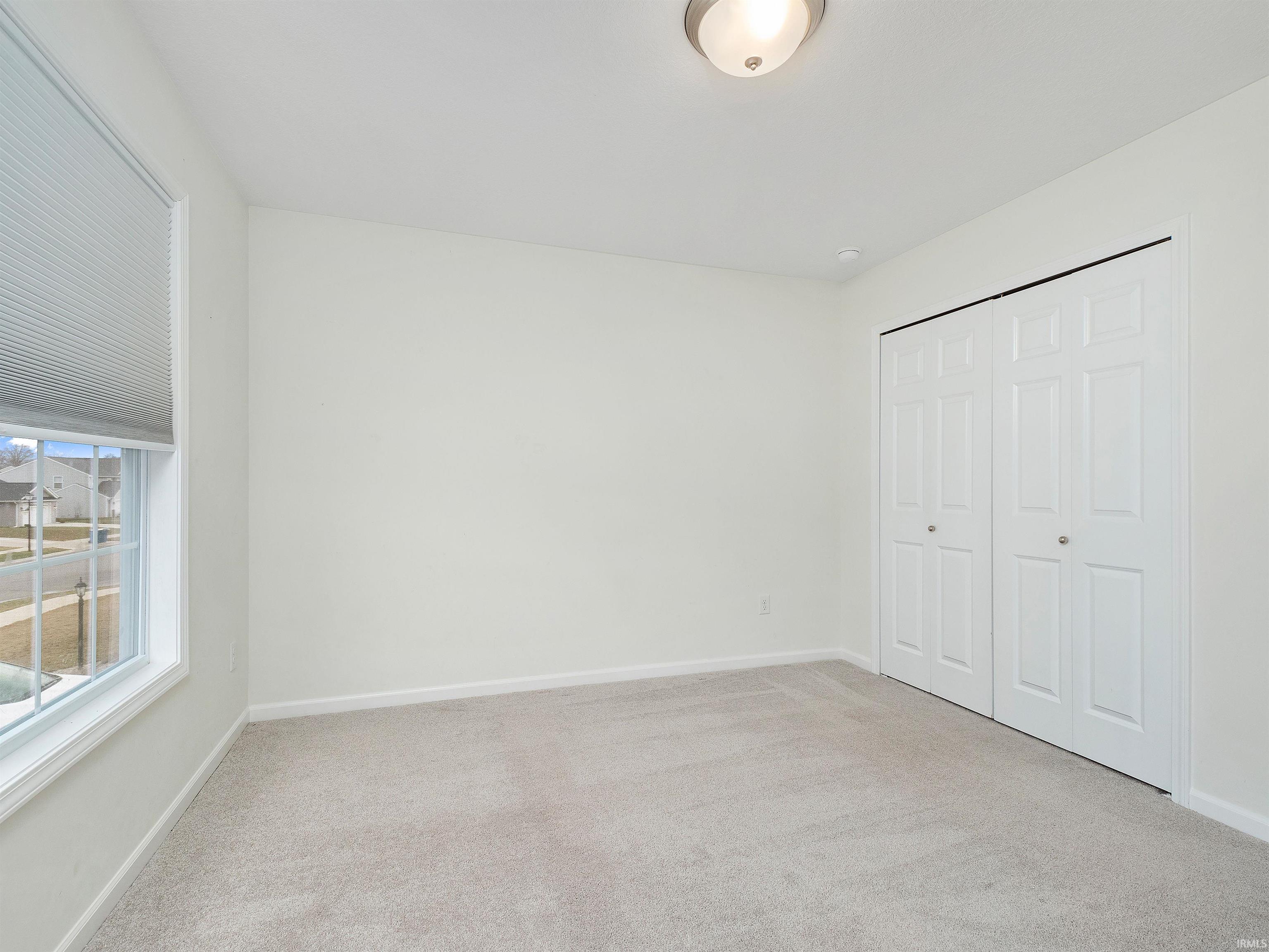 Unfurnished bedroom featuring light colored carpet and a closet