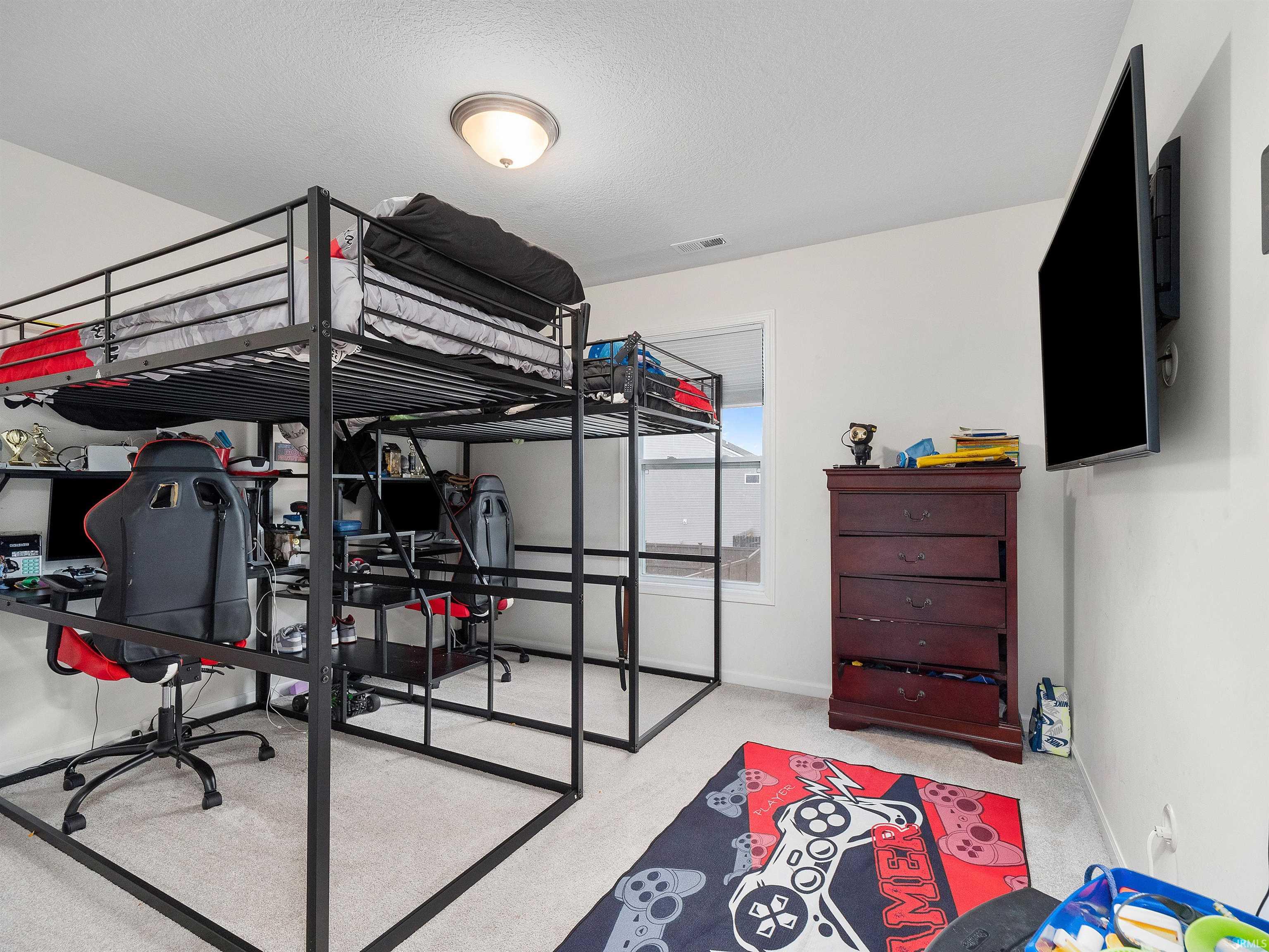 Bedroom featuring an office area, light colored carpet, and a textured ceiling