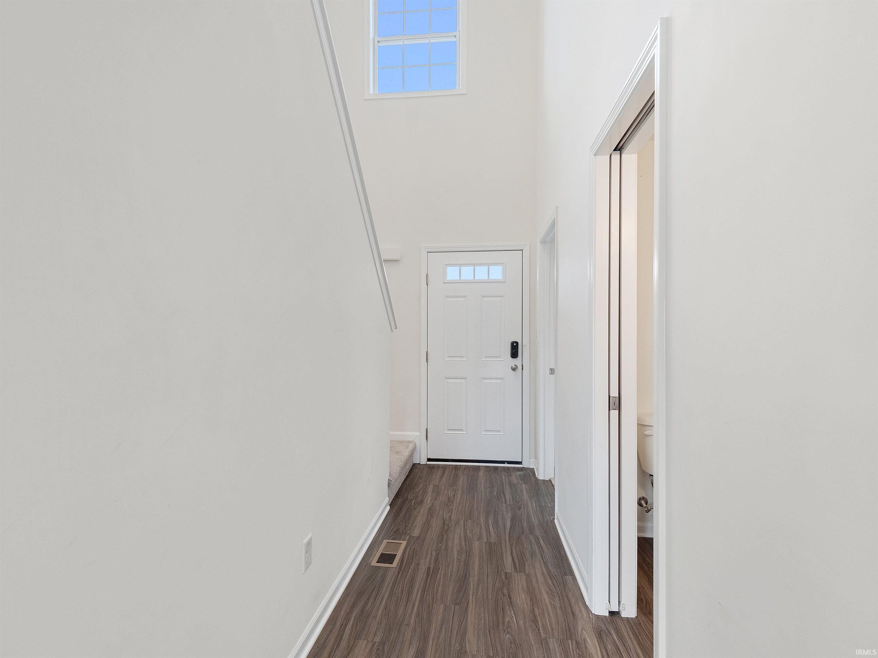 Entryway with a towering ceiling and wood finished floors