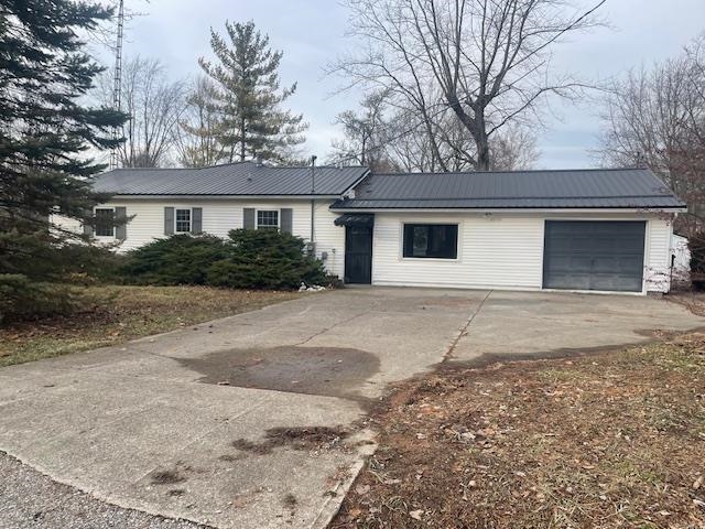 Single story home featuring a metal roof, driveway, a garage, and a standing seam roof