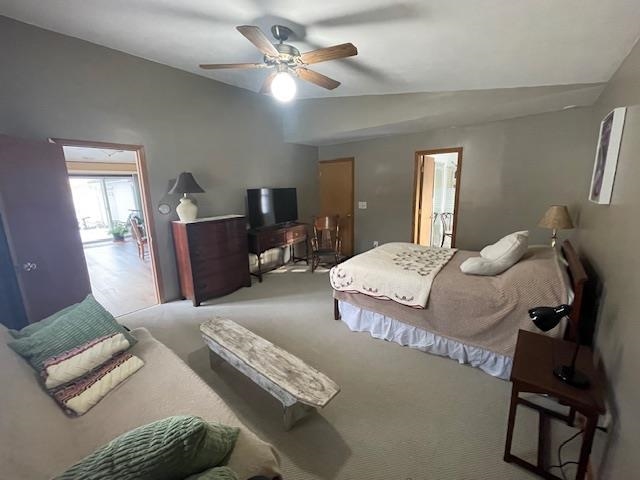 Bedroom with vaulted ceiling, carpet, and a ceiling fan