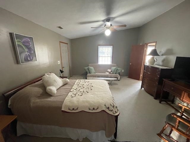 Carpeted bedroom featuring lofted ceiling and a ceiling fan