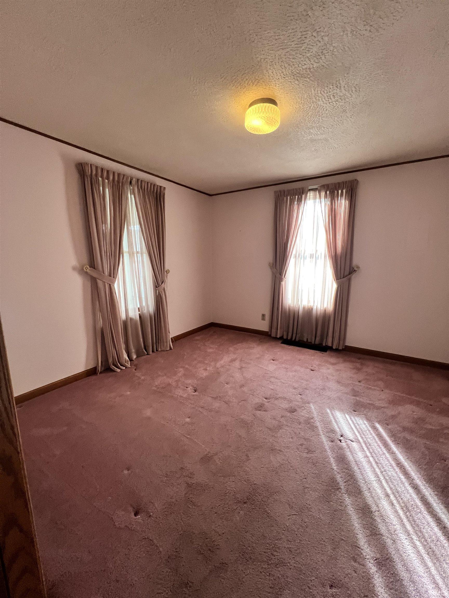 Empty room with a textured ceiling and carpet