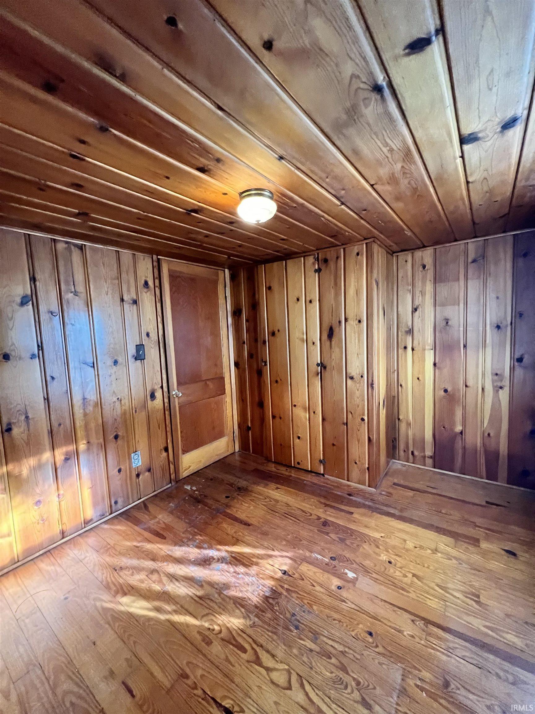 Basement with dark wood finished floors, wooden walls, and wooden ceiling