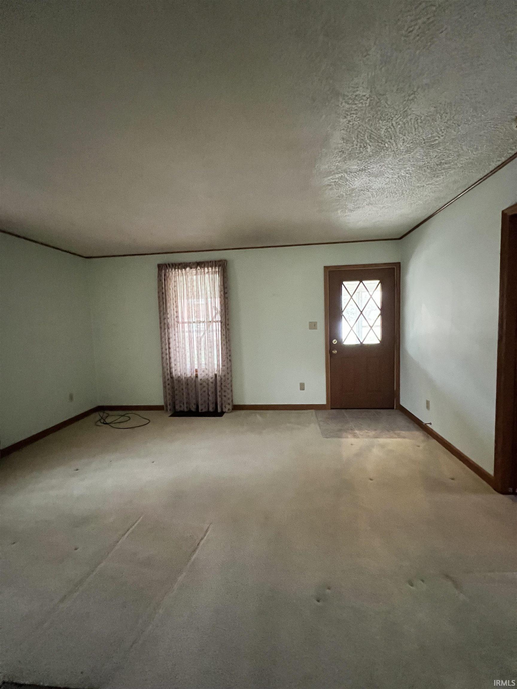 Carpeted foyer entrance with baseboards and a textured ceiling