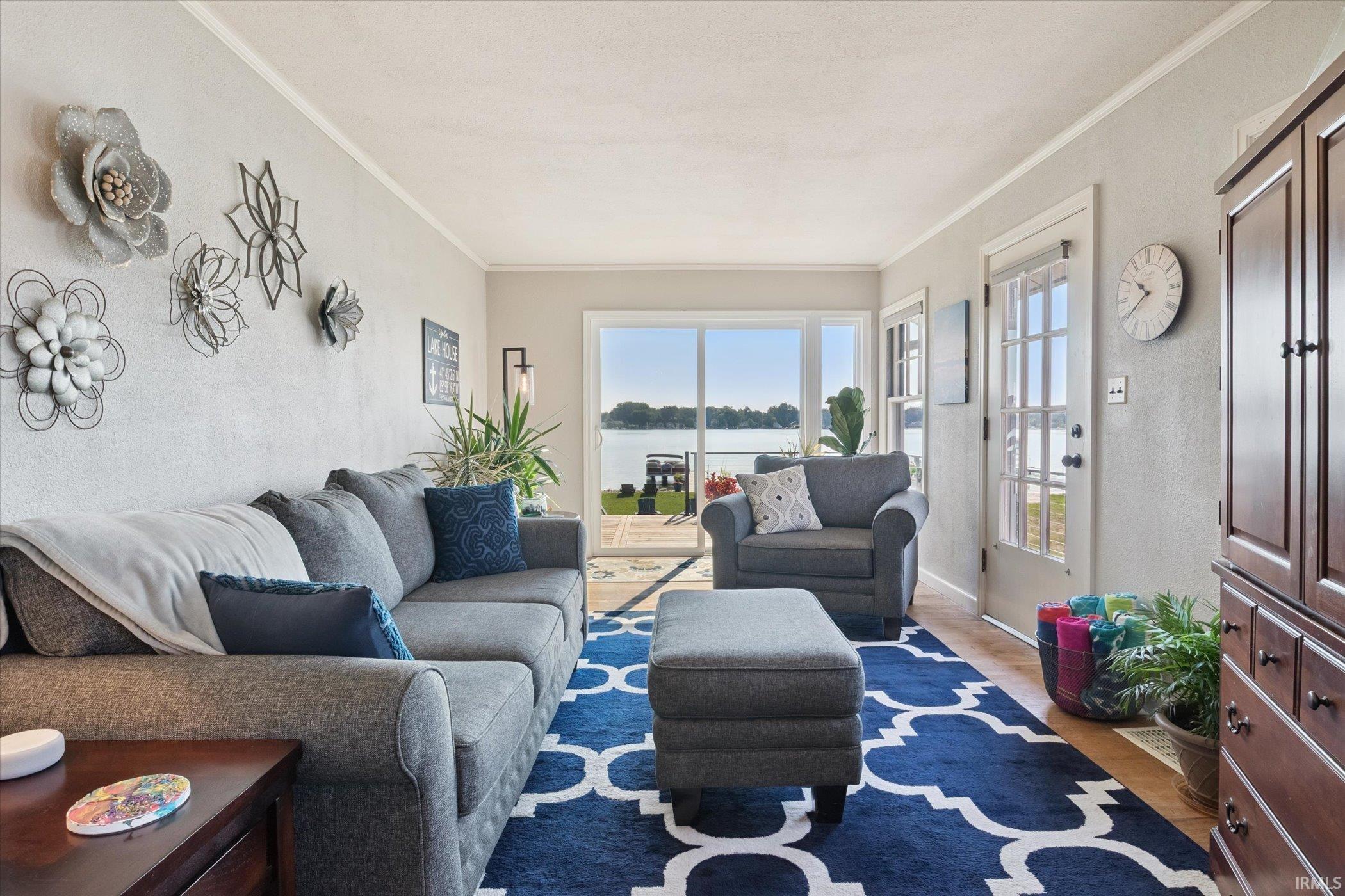 Living area with a water view, ornamental molding, and wood finished floors
