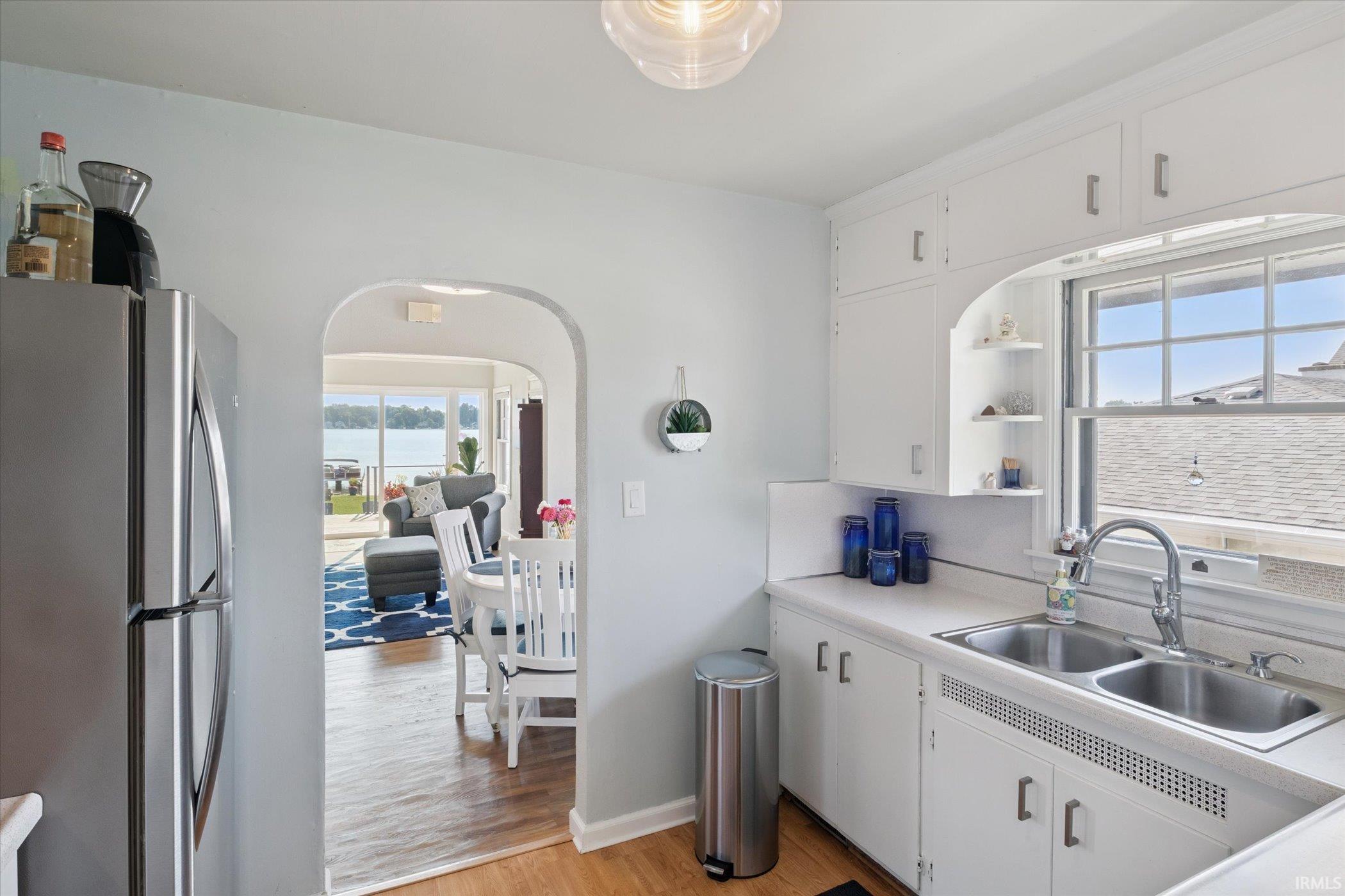 Kitchen with freestanding refrigerator, white cabinets, light countertops, light wood finished floors, and open shelves