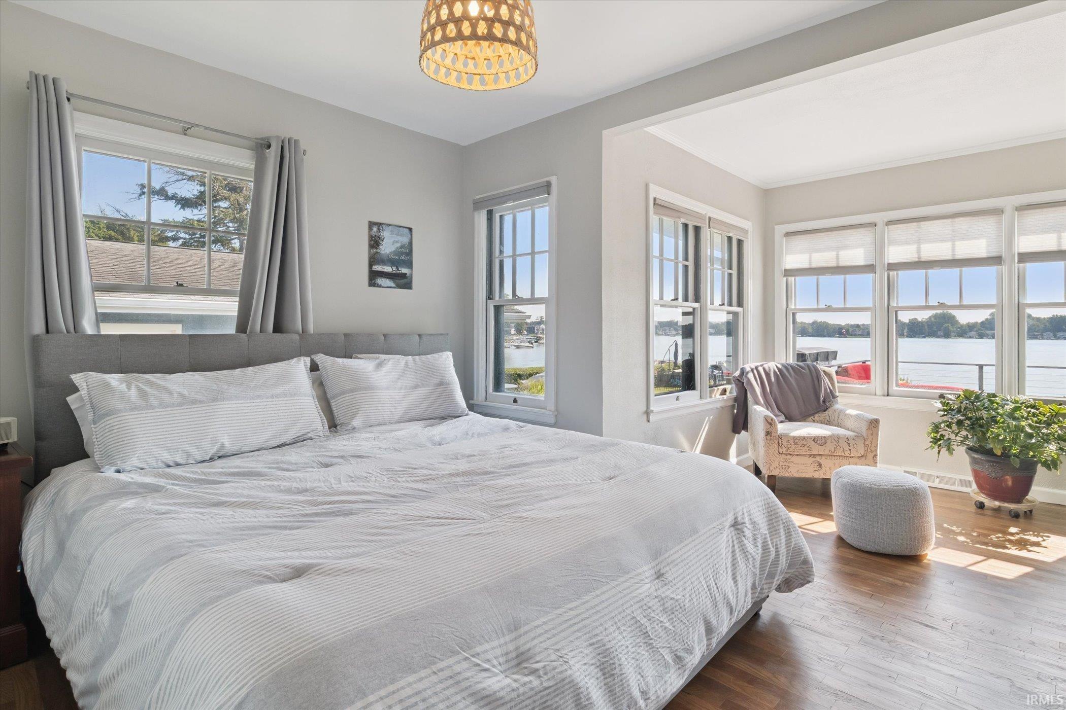 Bedroom with wood finished floors, a water view, and a chandelier