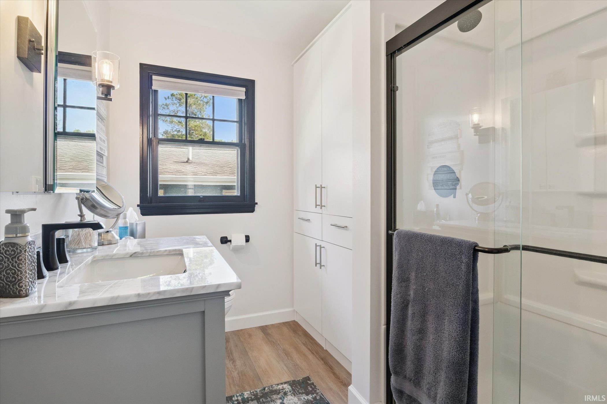 Bathroom with vanity, a stall shower, and light wood-type flooring