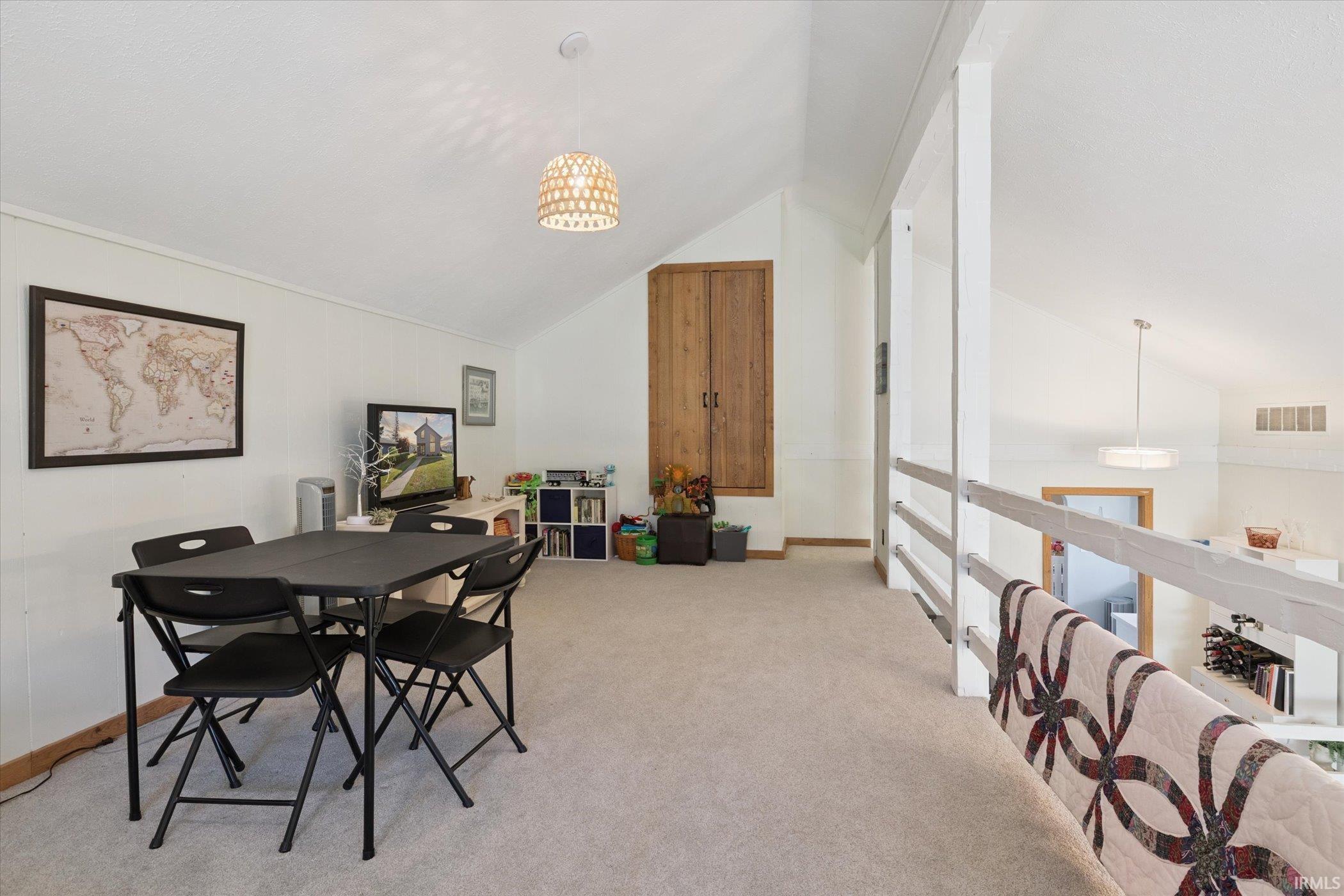Dining space featuring light carpet, a chandelier, and high vaulted ceiling