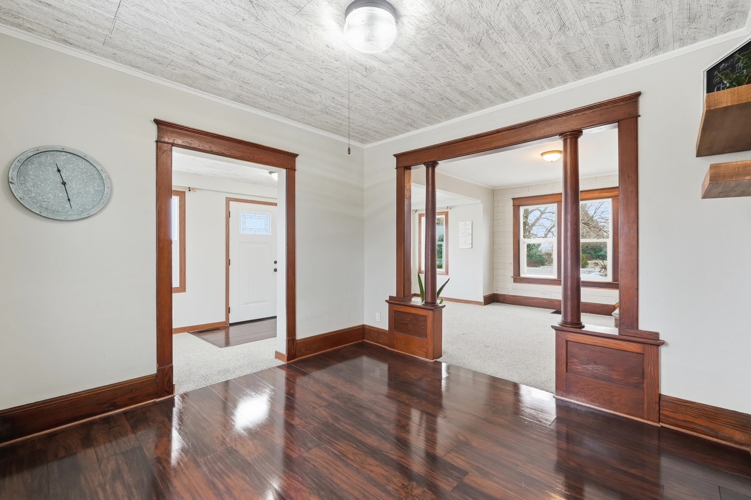 Unfurnished room with dark wood finished floors, crown molding, and decorative columns