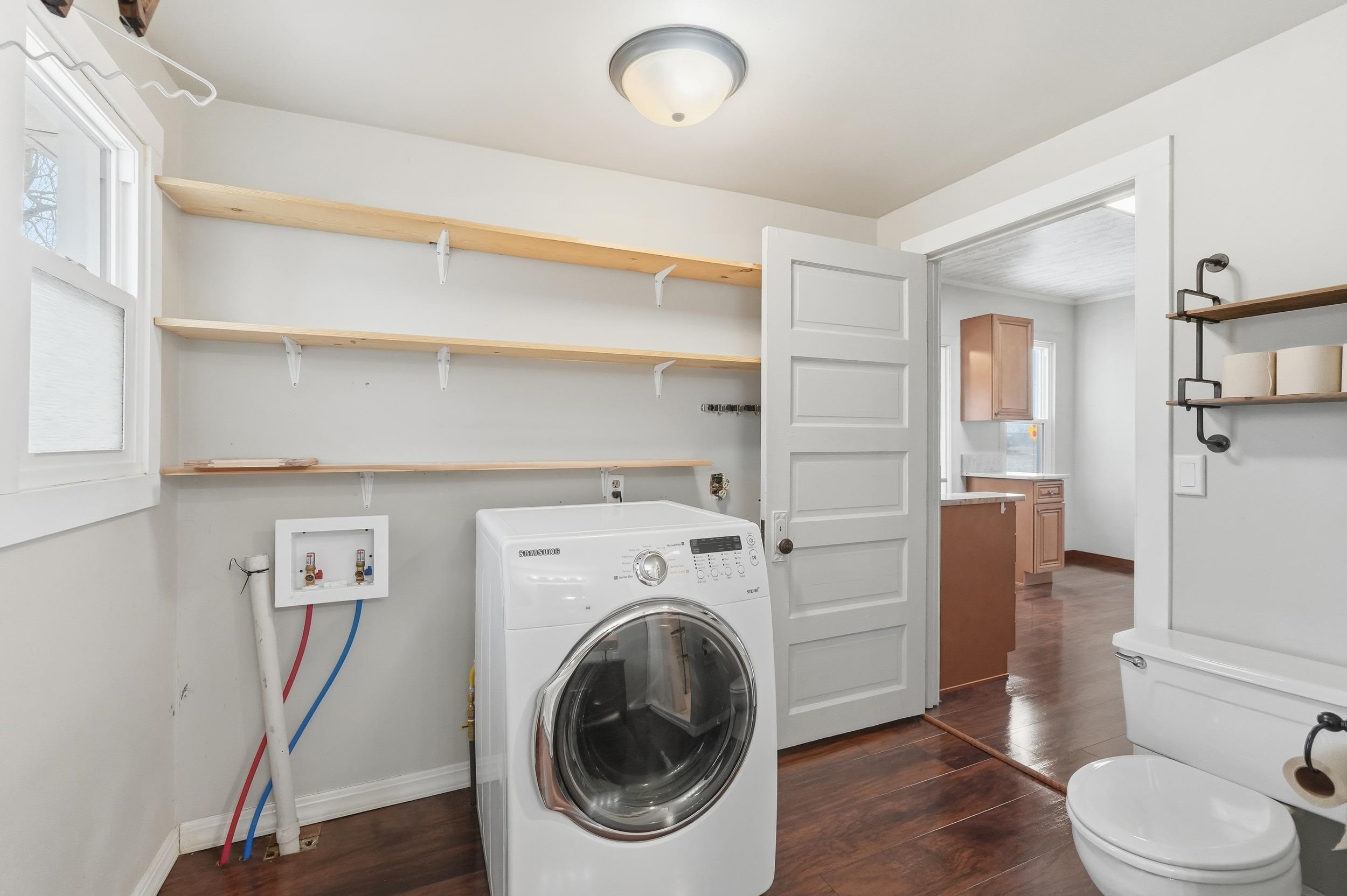 Washroom with washer / dryer and dark wood-type flooring