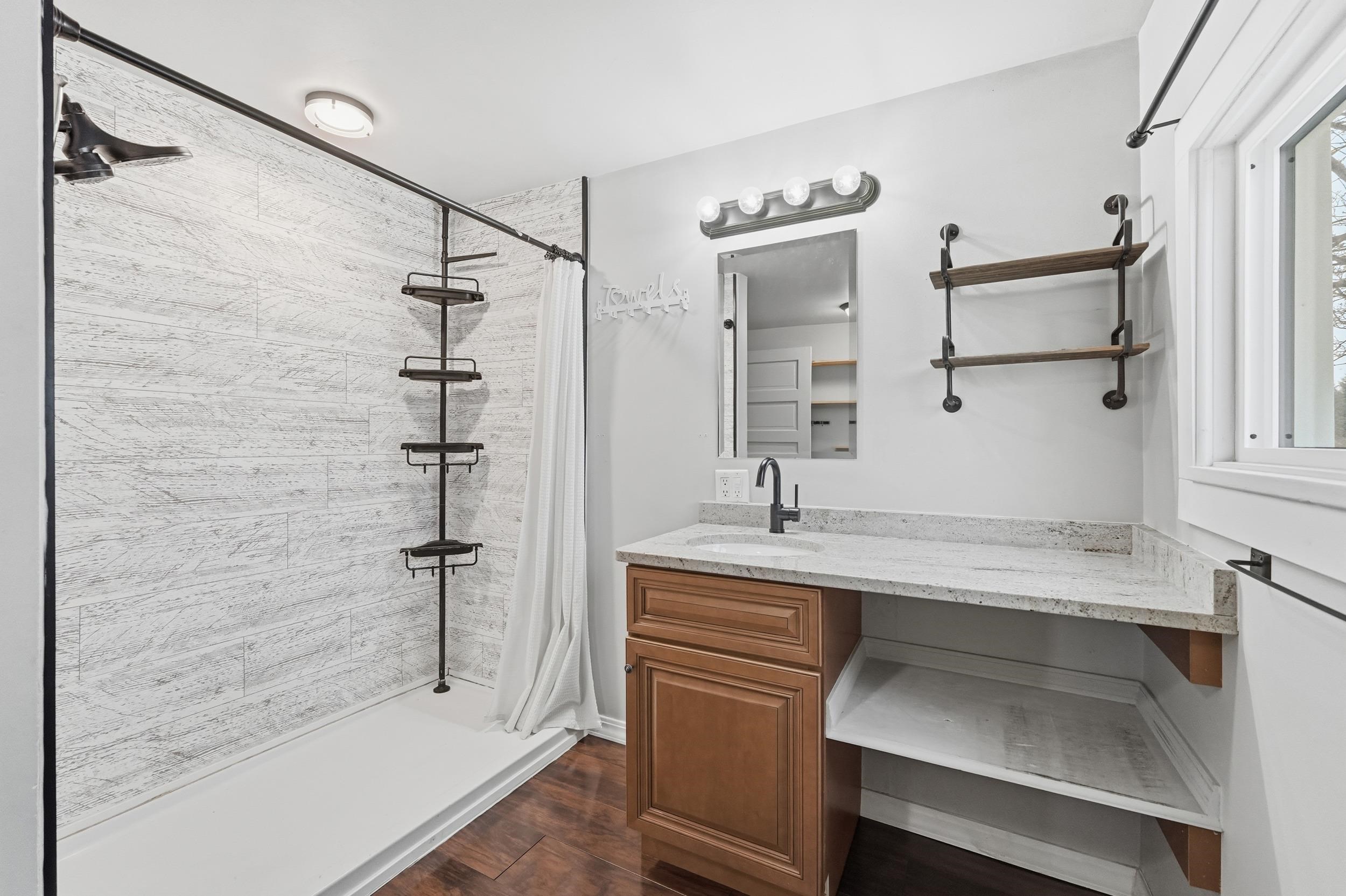 Full bathroom featuring a stall shower, vanity, and dark wood-style floors