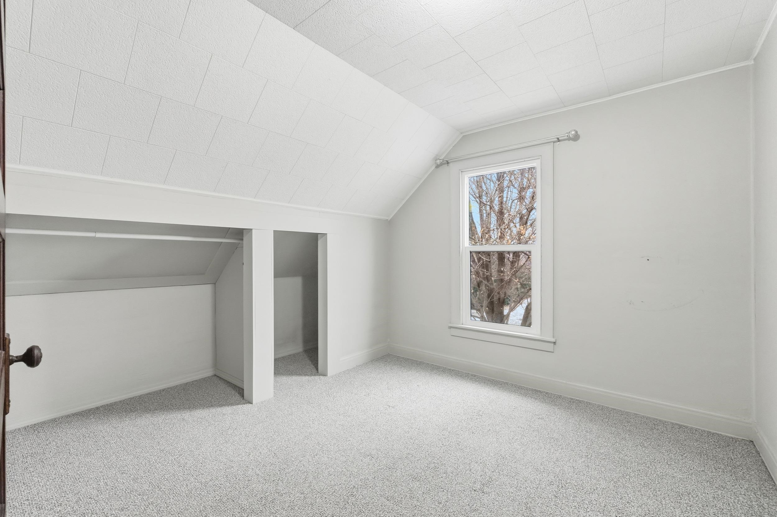 Bonus room with light colored carpet and lofted ceiling