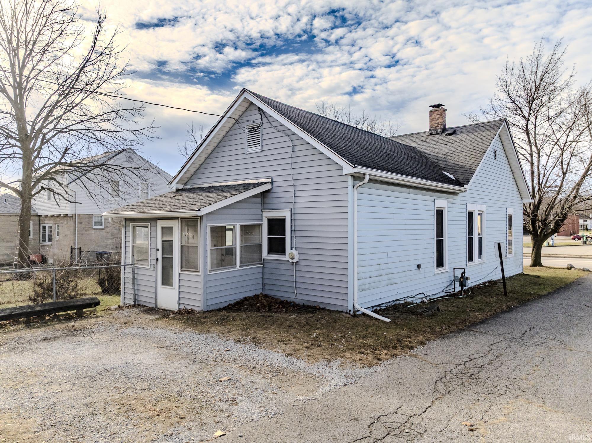View of home's exterior with a sunroom, roof with shingles, and a chimney
