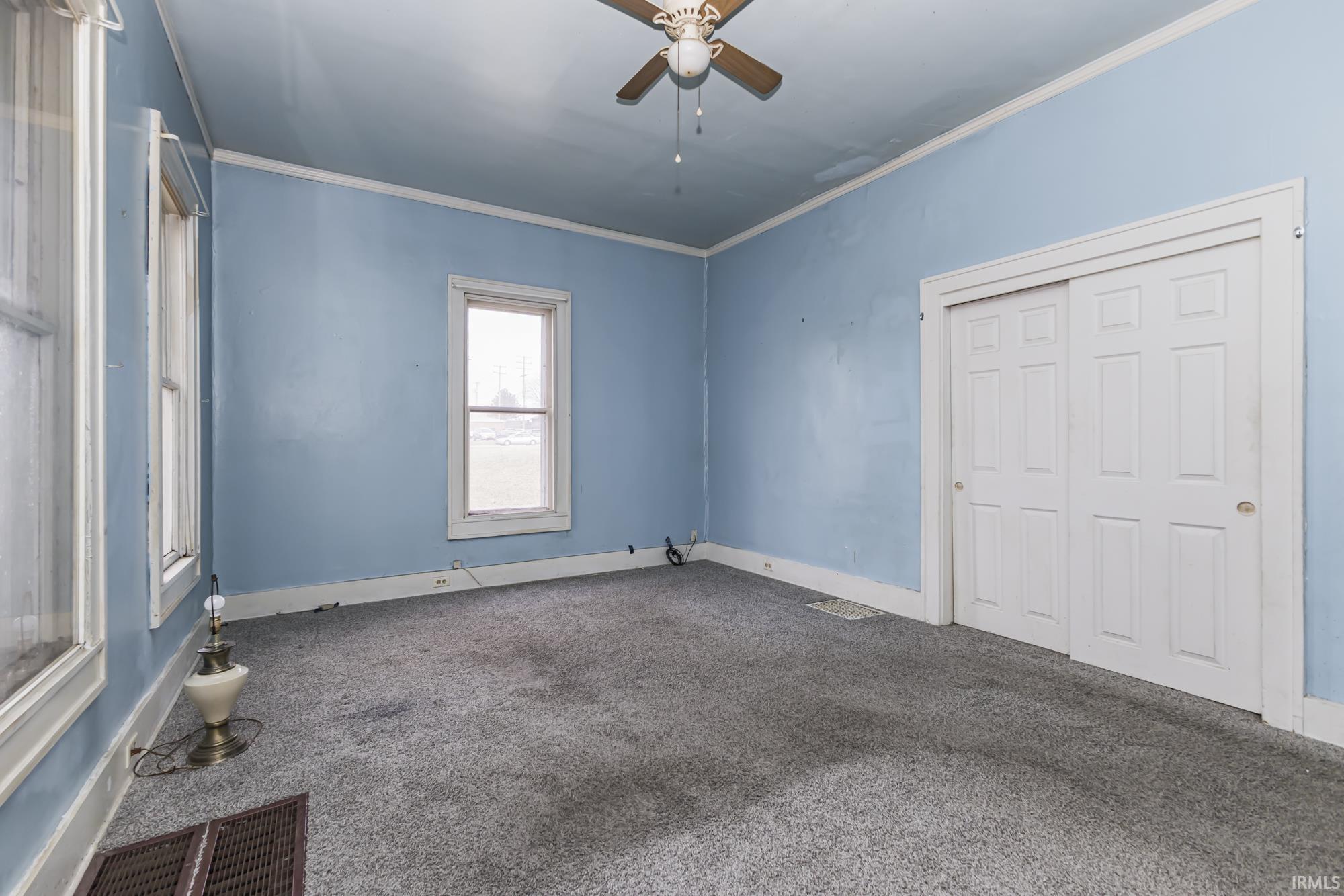 Unfurnished bedroom featuring carpet floors, crown molding, a ceiling fan, and a closet