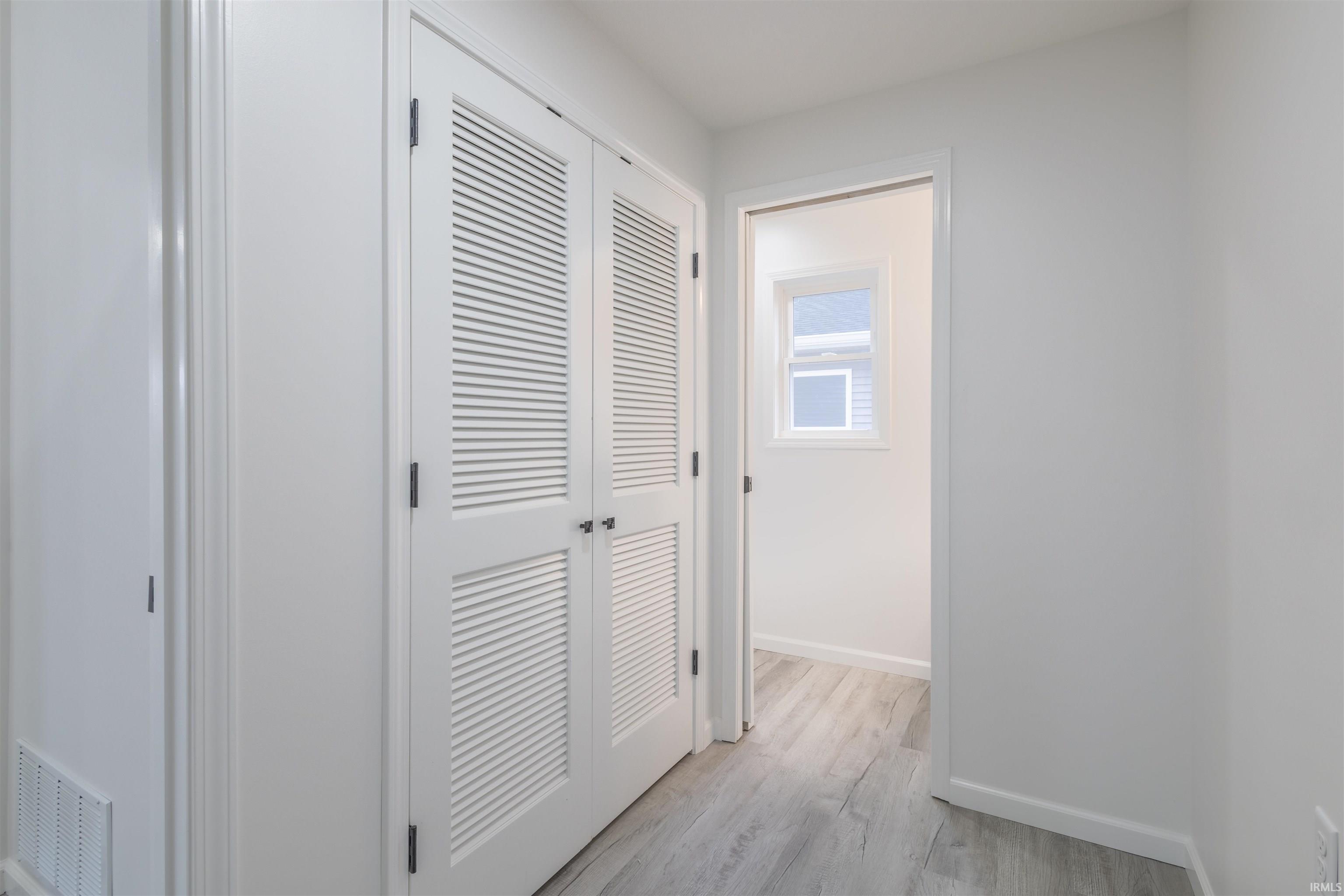 Hallway featuring light wood-type flooring and baseboards