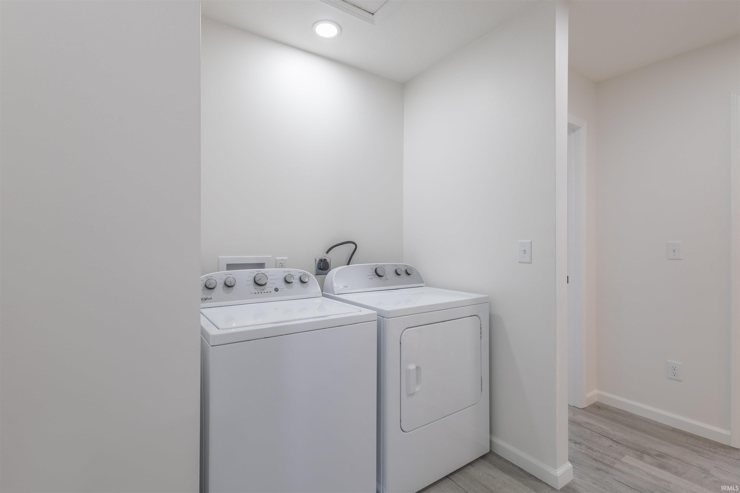 Laundry area with independent washer and dryer, light wood-type flooring, and recessed lighting