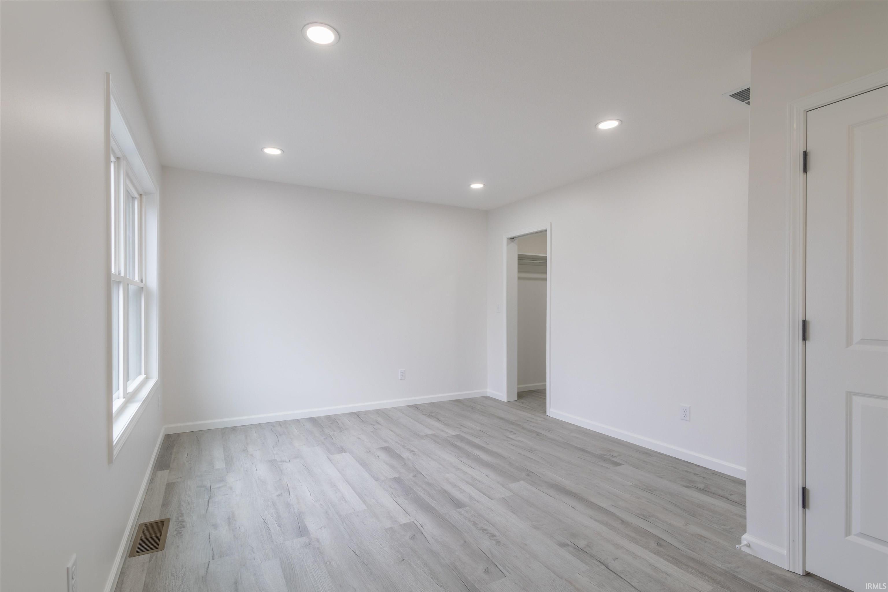 Unfurnished bedroom featuring a walk in closet, light wood finished floors, and recessed lighting