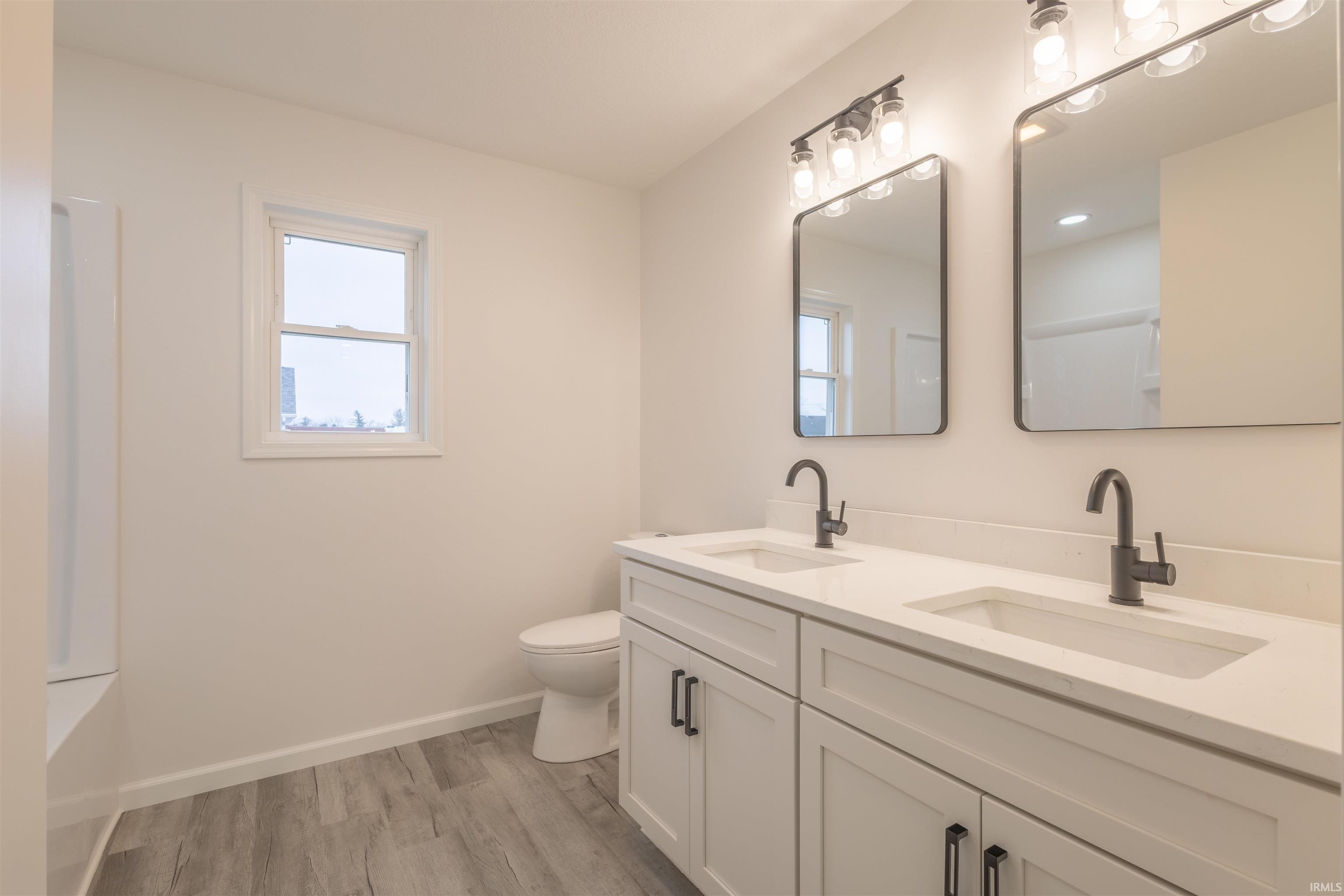 Full bathroom featuring double vanity and light wood-style floors