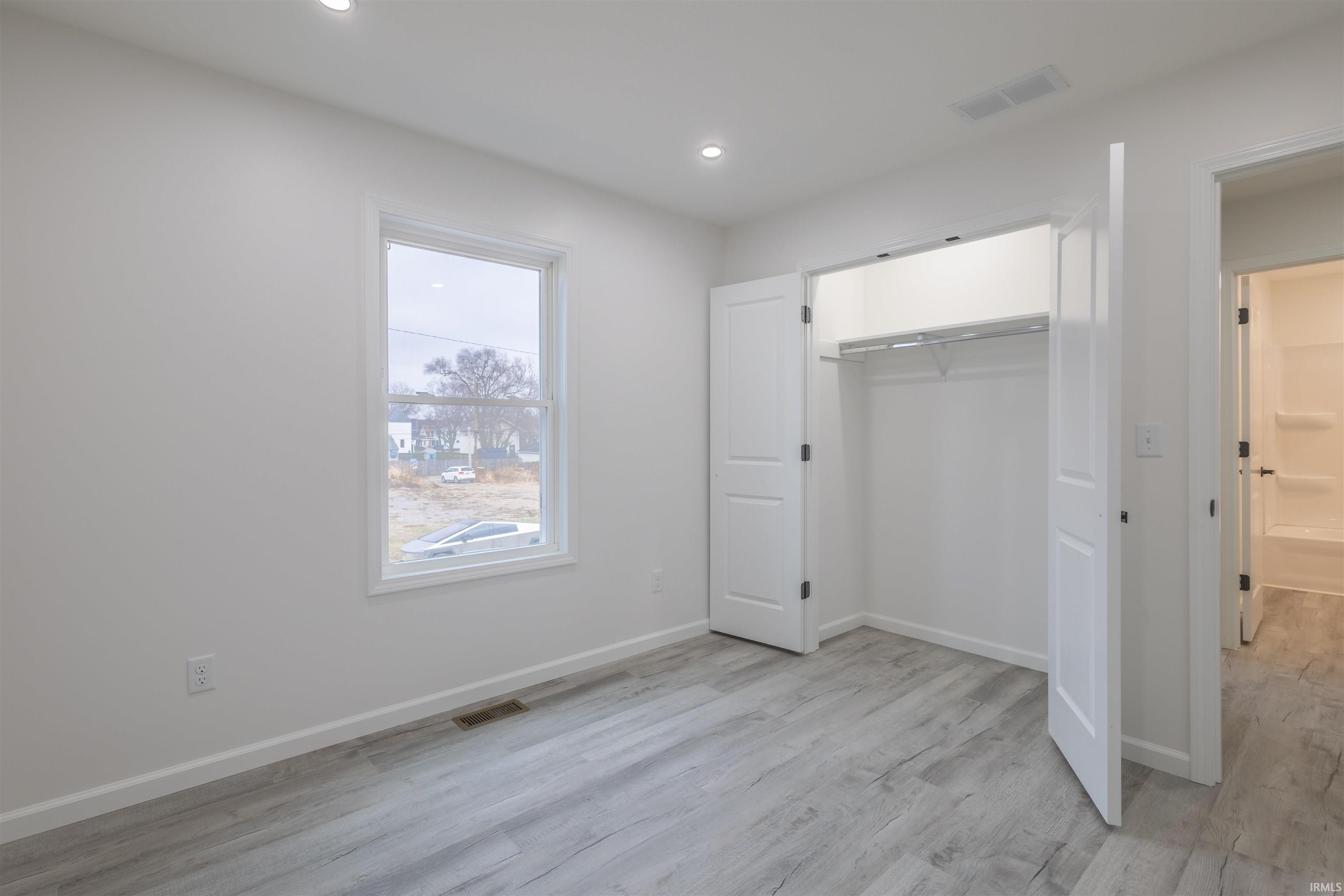 Unfurnished bedroom featuring light wood-type flooring, a closet, and recessed lighting