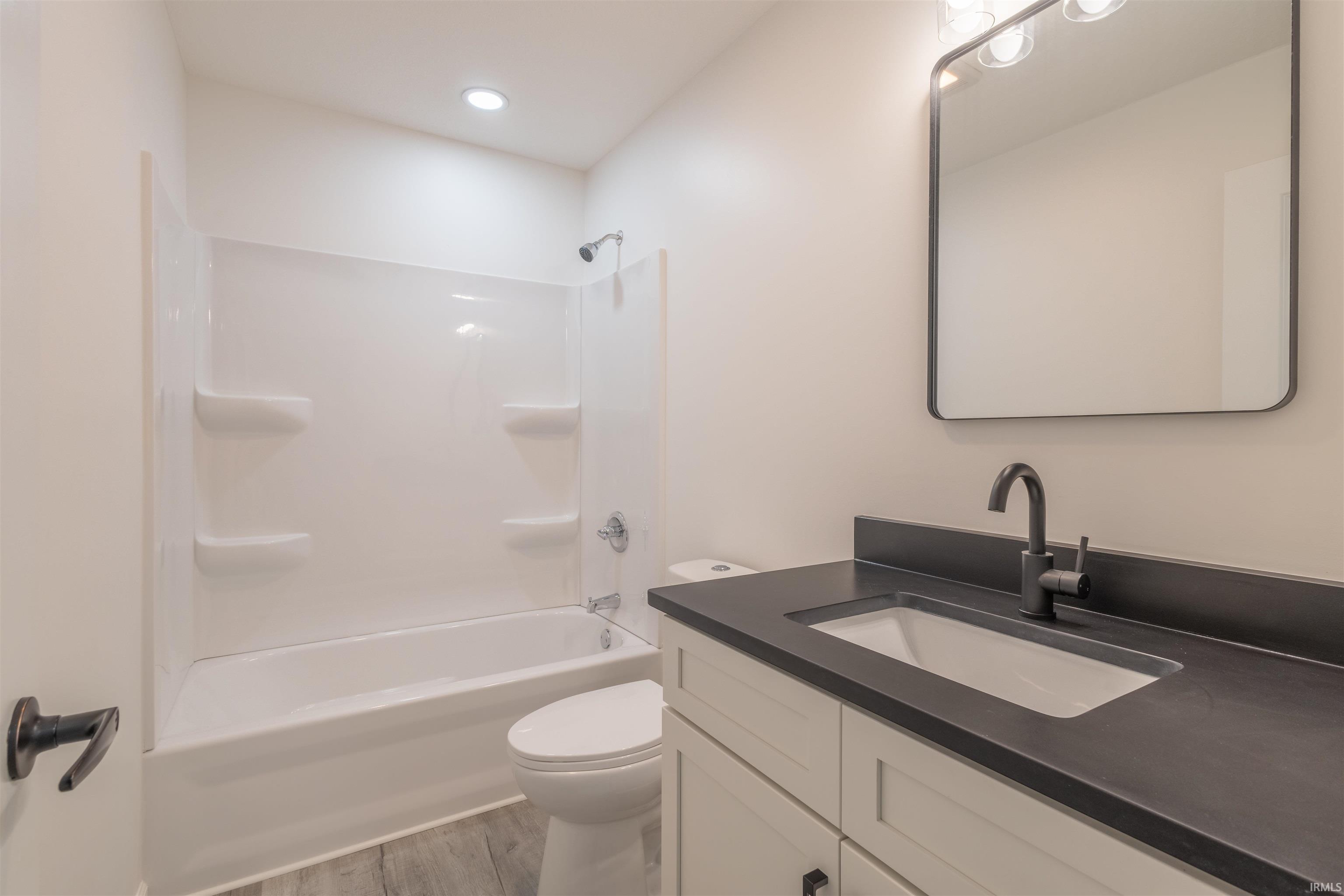 Full bathroom with shower / washtub combination, vanity, and light wood-type flooring
