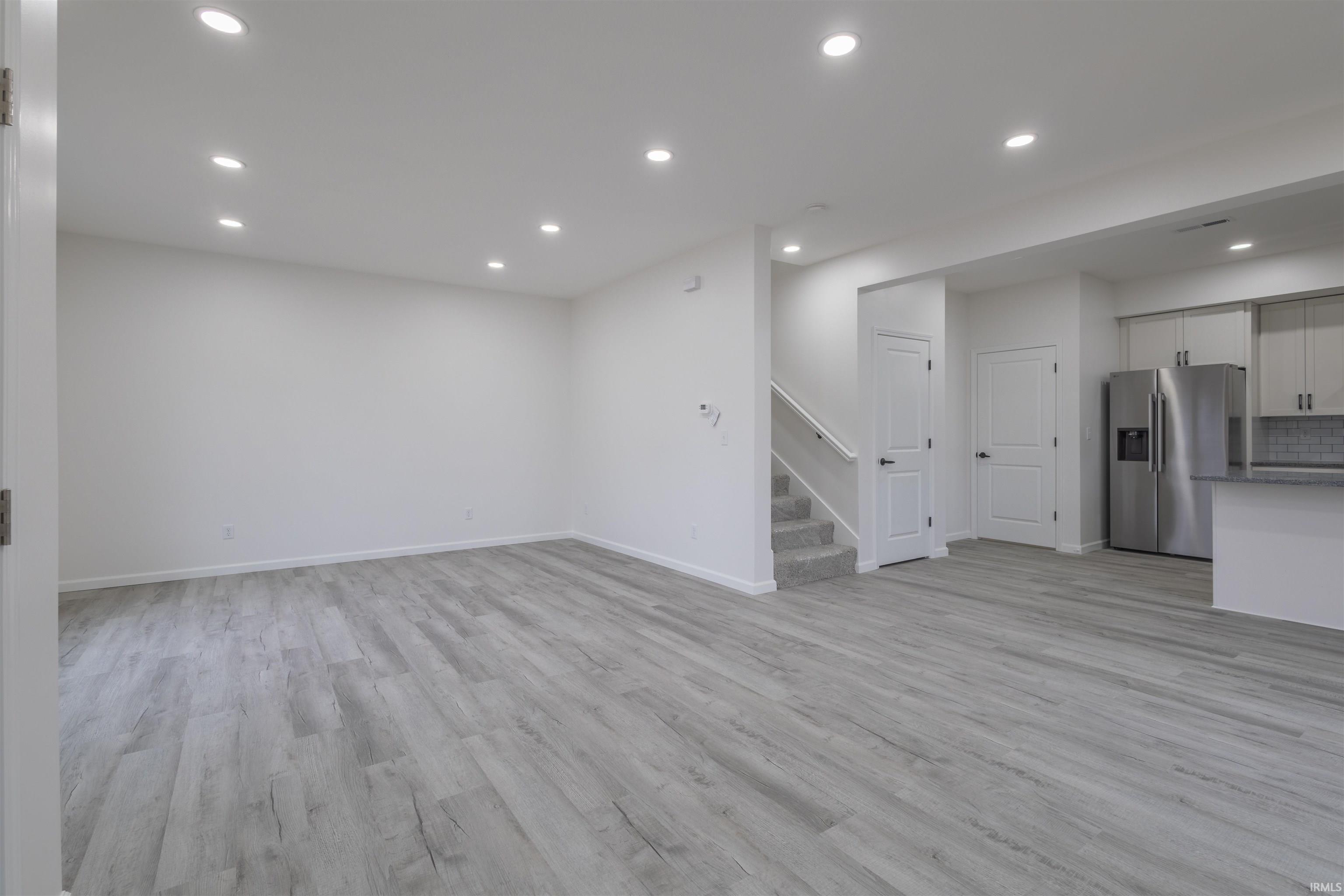 Unfurnished living room with recessed lighting, light wood-type flooring, and stairs