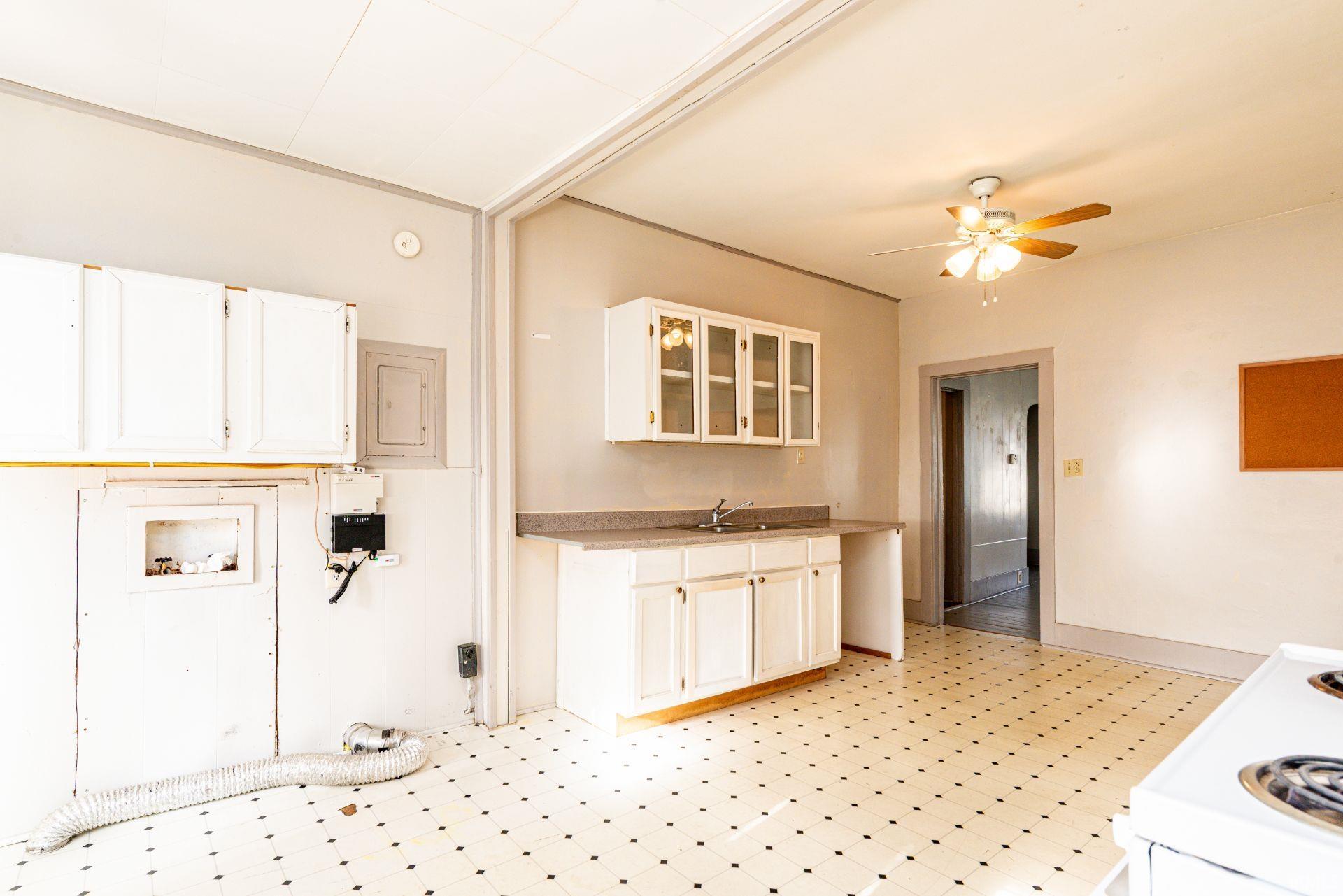 Kitchen featuring light flooring, white cabinetry, electric panel, and glass insert cabinets
