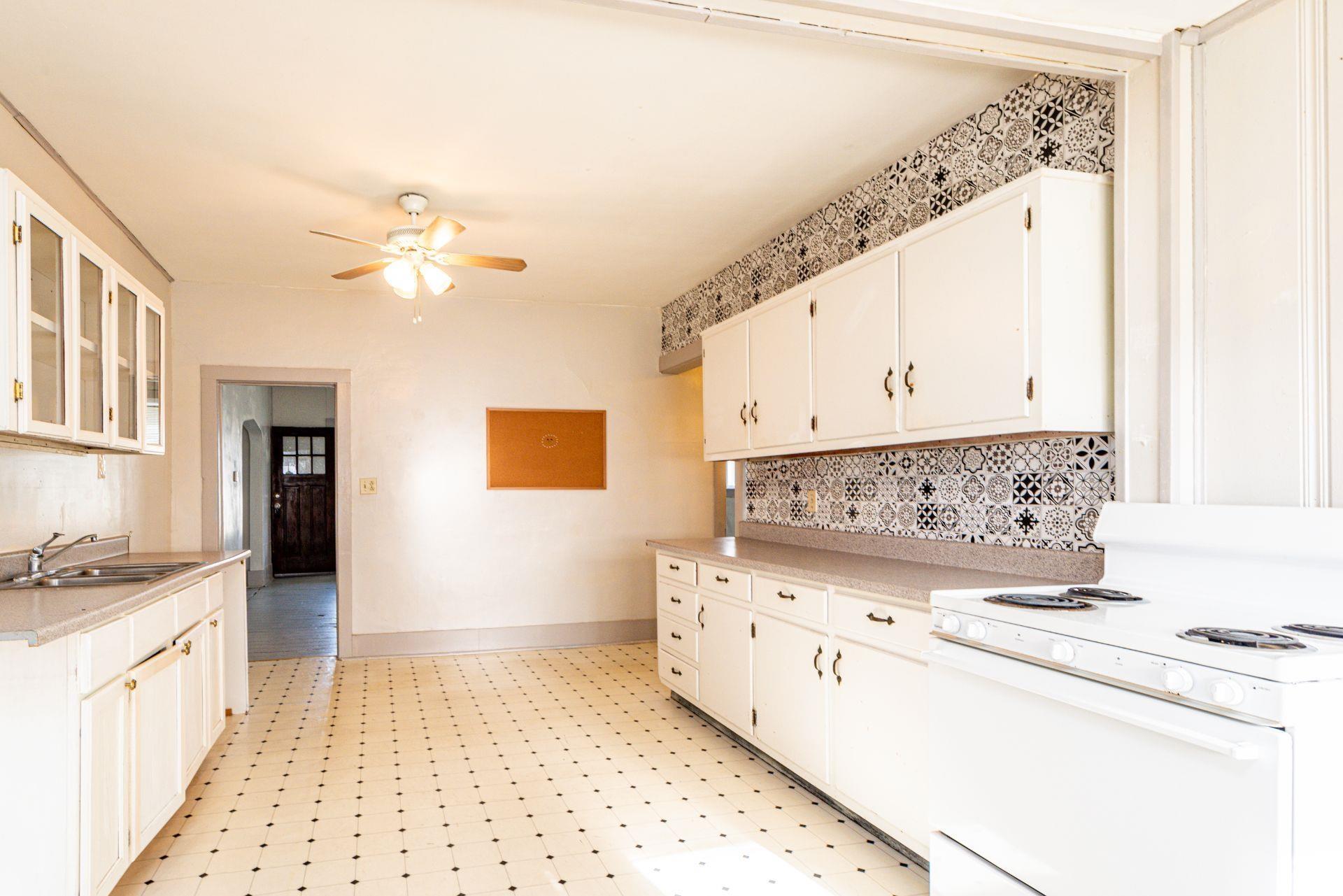 Kitchen with electric range, light floors, light countertops, and glass insert cabinets