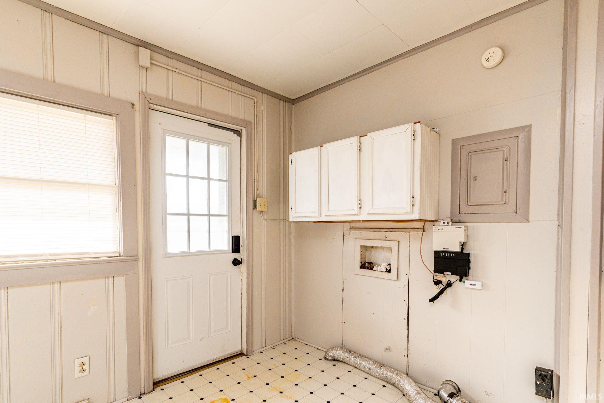 Laundry area with light flooring, electric panel, cabinet space, and hookup for a washing machine