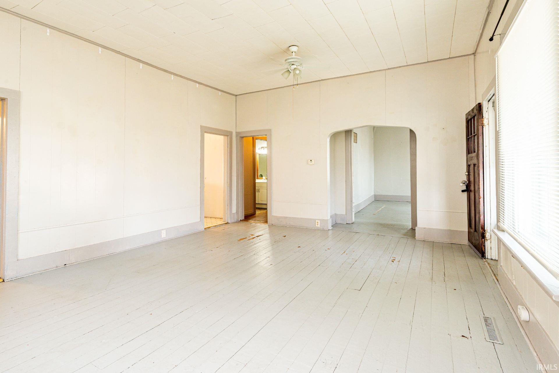 Empty room with arched walkways, a ceiling fan, and hardwood / wood-style floors