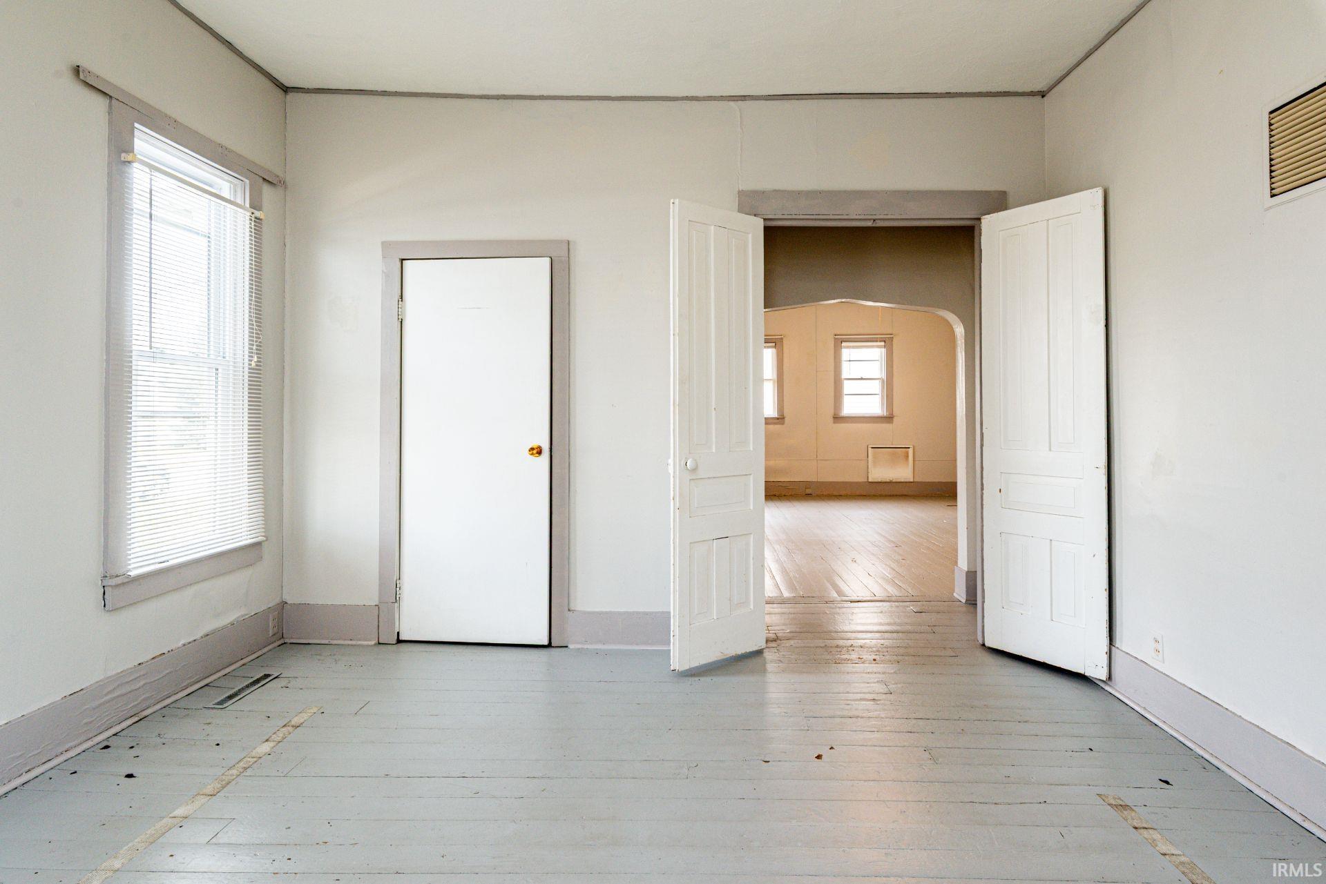 Unfurnished room featuring arched walkways and light wood-type flooring