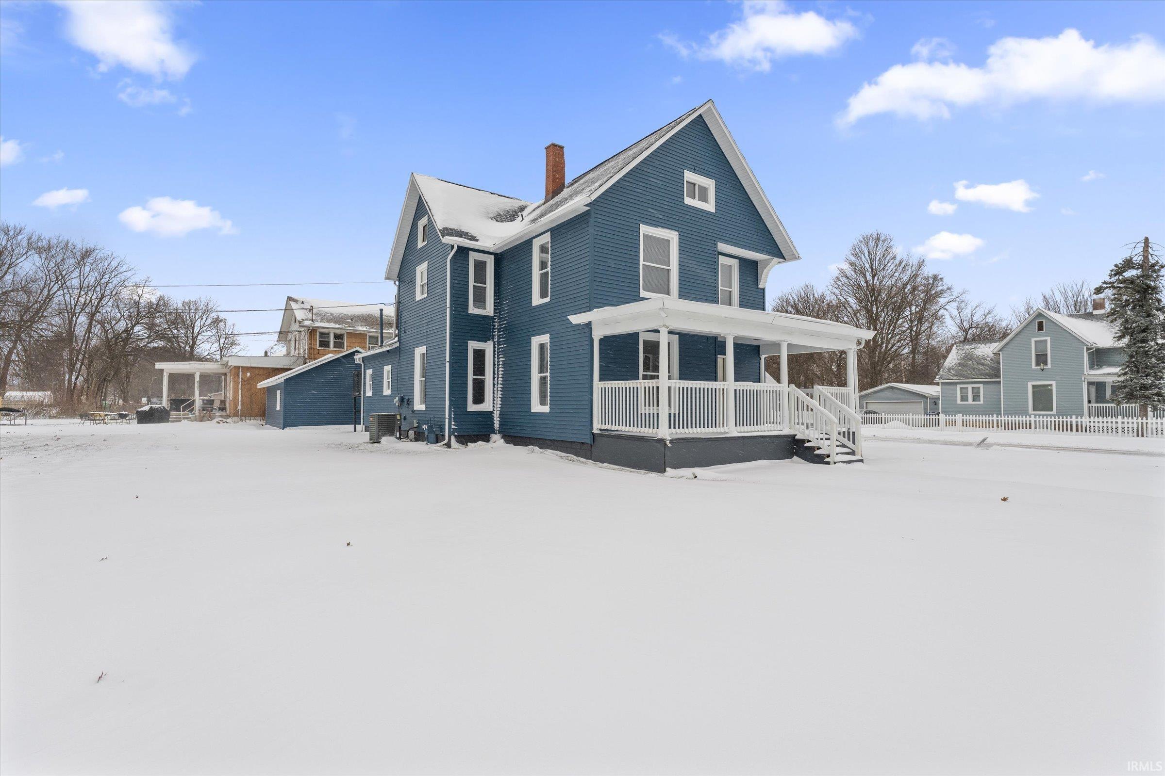 Snow covered property featuring a chimney and a porch