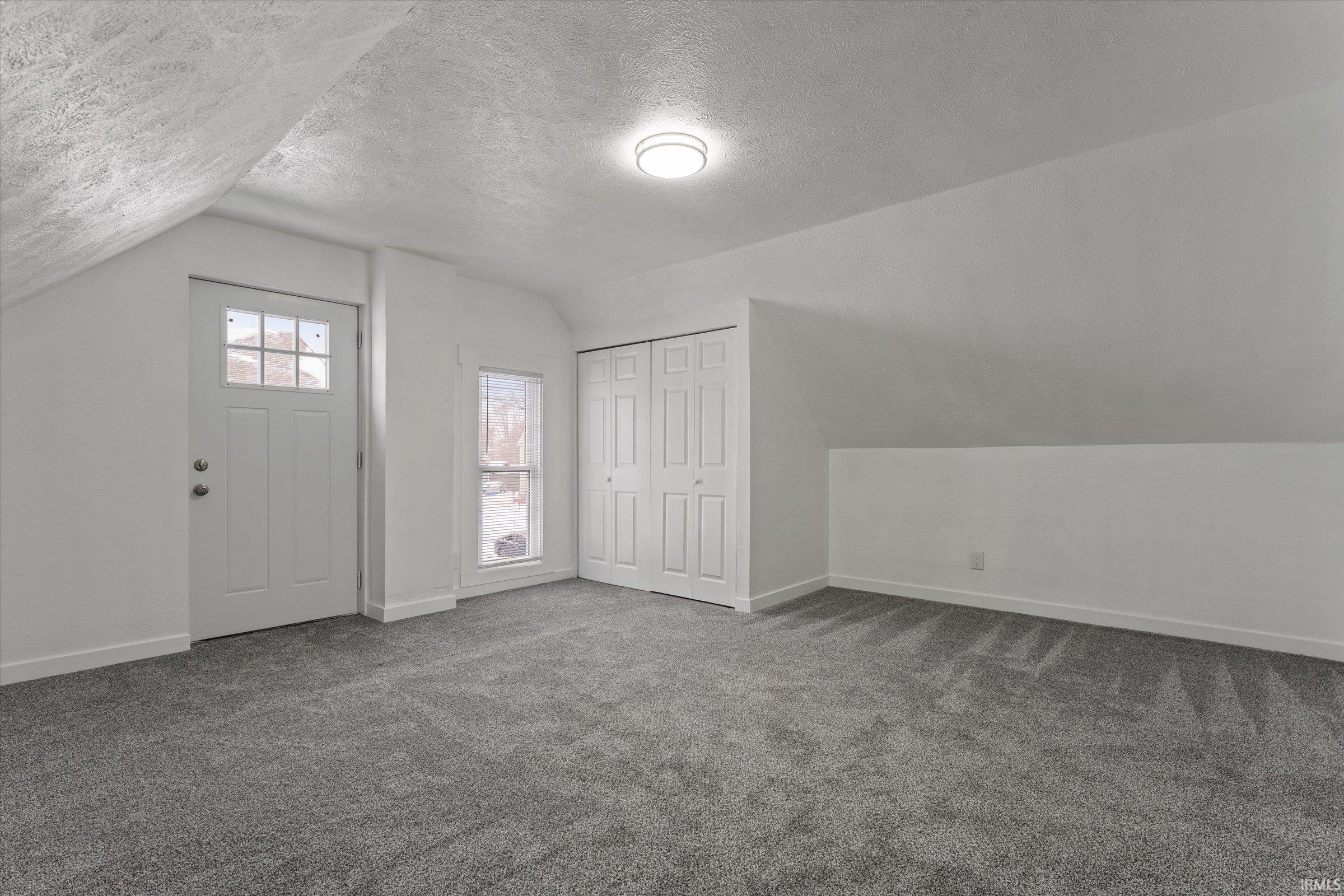 Bonus room with a textured ceiling, lofted ceiling, and carpet flooring