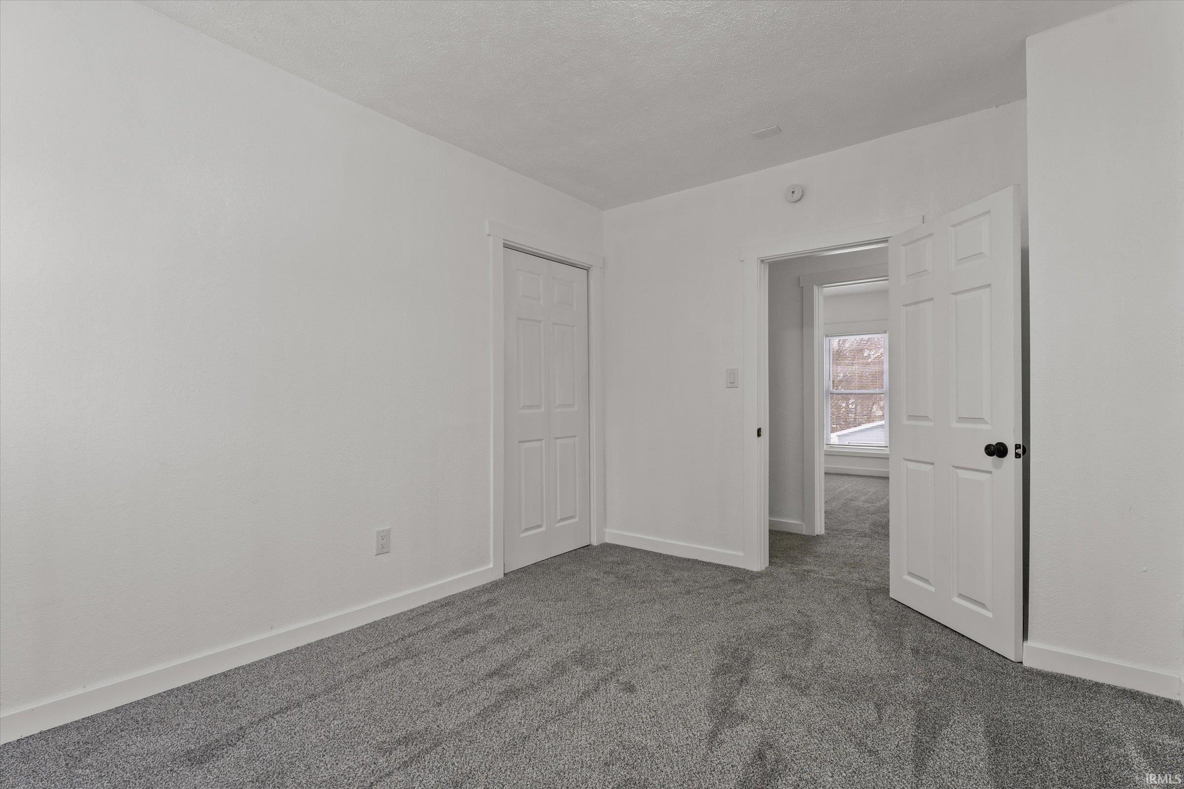 Unfurnished room with dark carpet and a textured ceiling